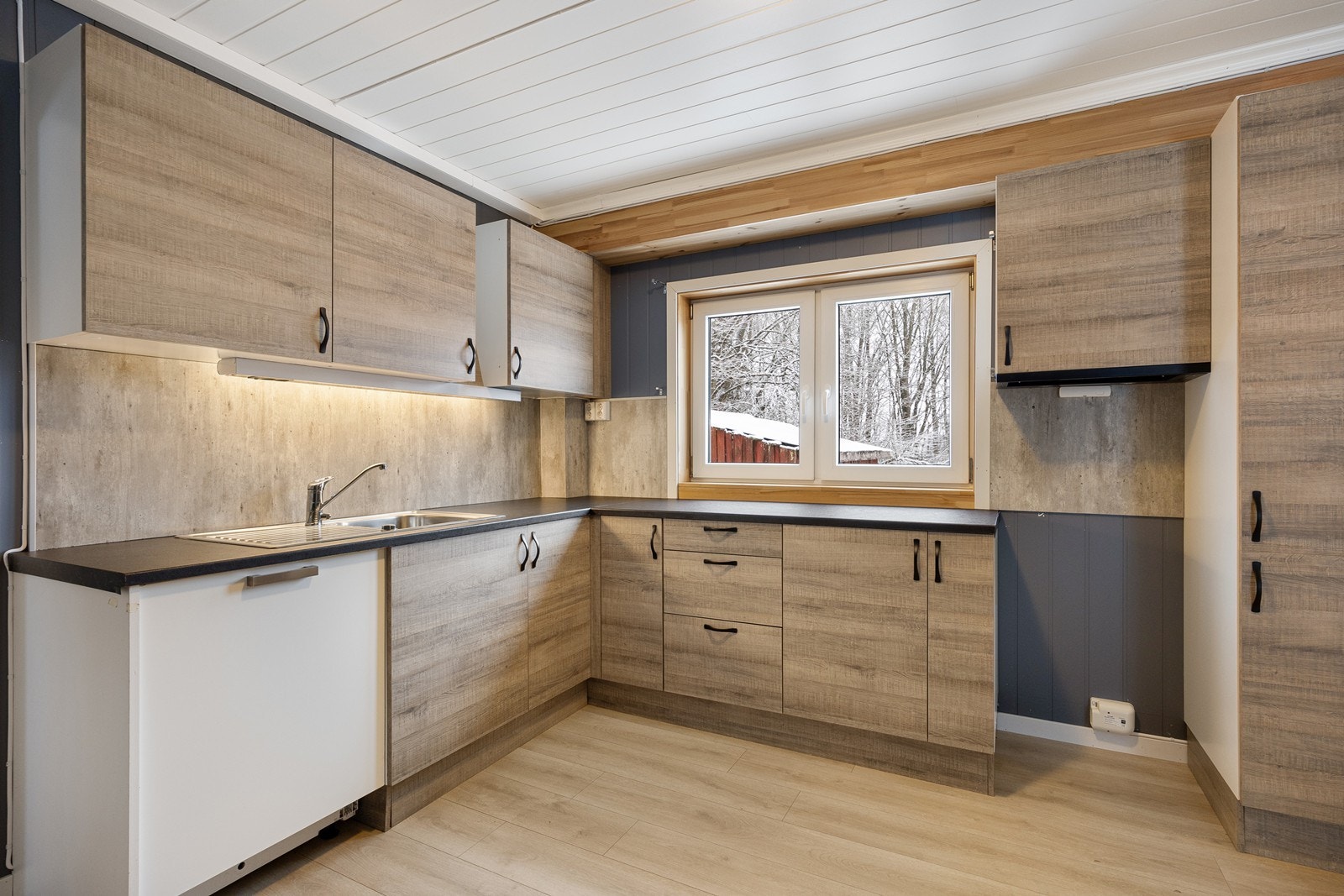 Innredningen har glatte fronter, og mørk laminatbenkeplate med nedfelt oppvaskkum i stål. Galleribilde