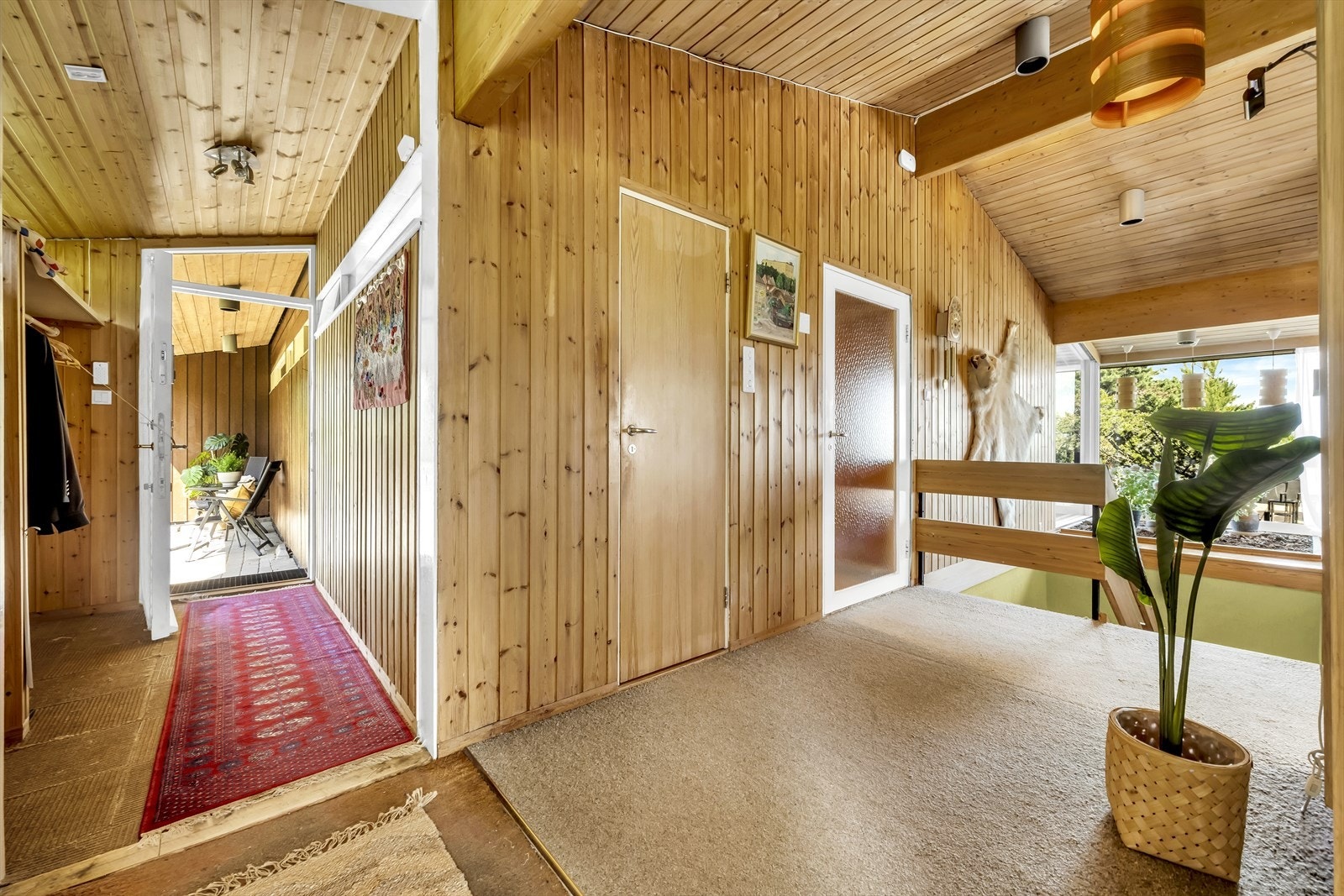 Fra vindfanget kommer man inn til gangen mellom kjøkken, trappeløp, vaskerom, gang til soveromsavdelingen (dør med glassfelt) og inn til stuen. Galleribilde