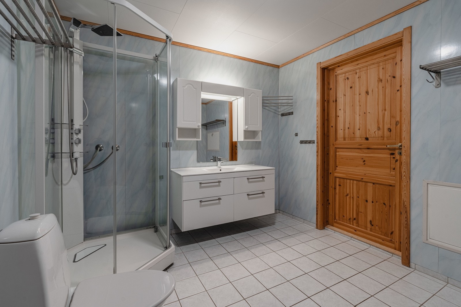 Badet er flislagt på gulv og er utstyrt med dusjkabinett Galleribilde