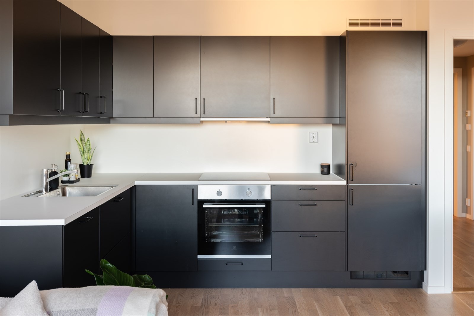 Det ble gjort tilvalg på kjøkken med fronter i matt sort. Kjøkkenet er av svært god størrelse sammenlignet med standarden for 2-romsleiligheter. Her får man rikelig med skap- og benkeplass. Galleribilde