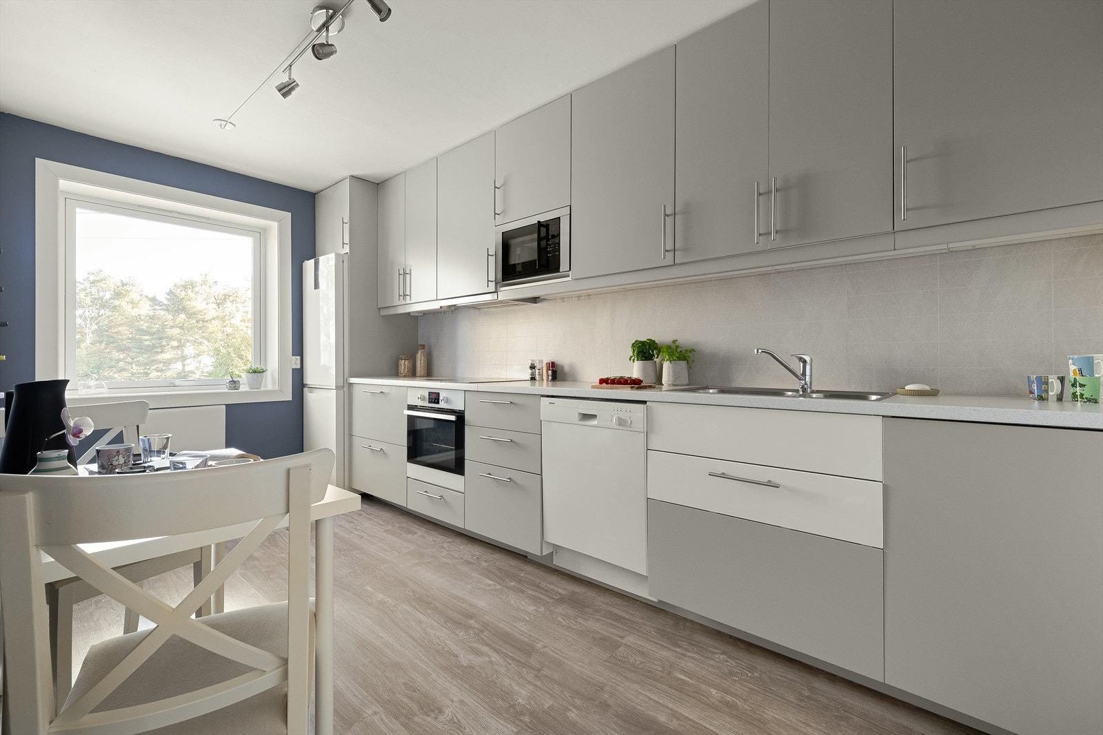 Lyst og pent IKEA kjøkken med rikelig oppbevaringsplass i takhøye skap og skuffer. Galleribilde