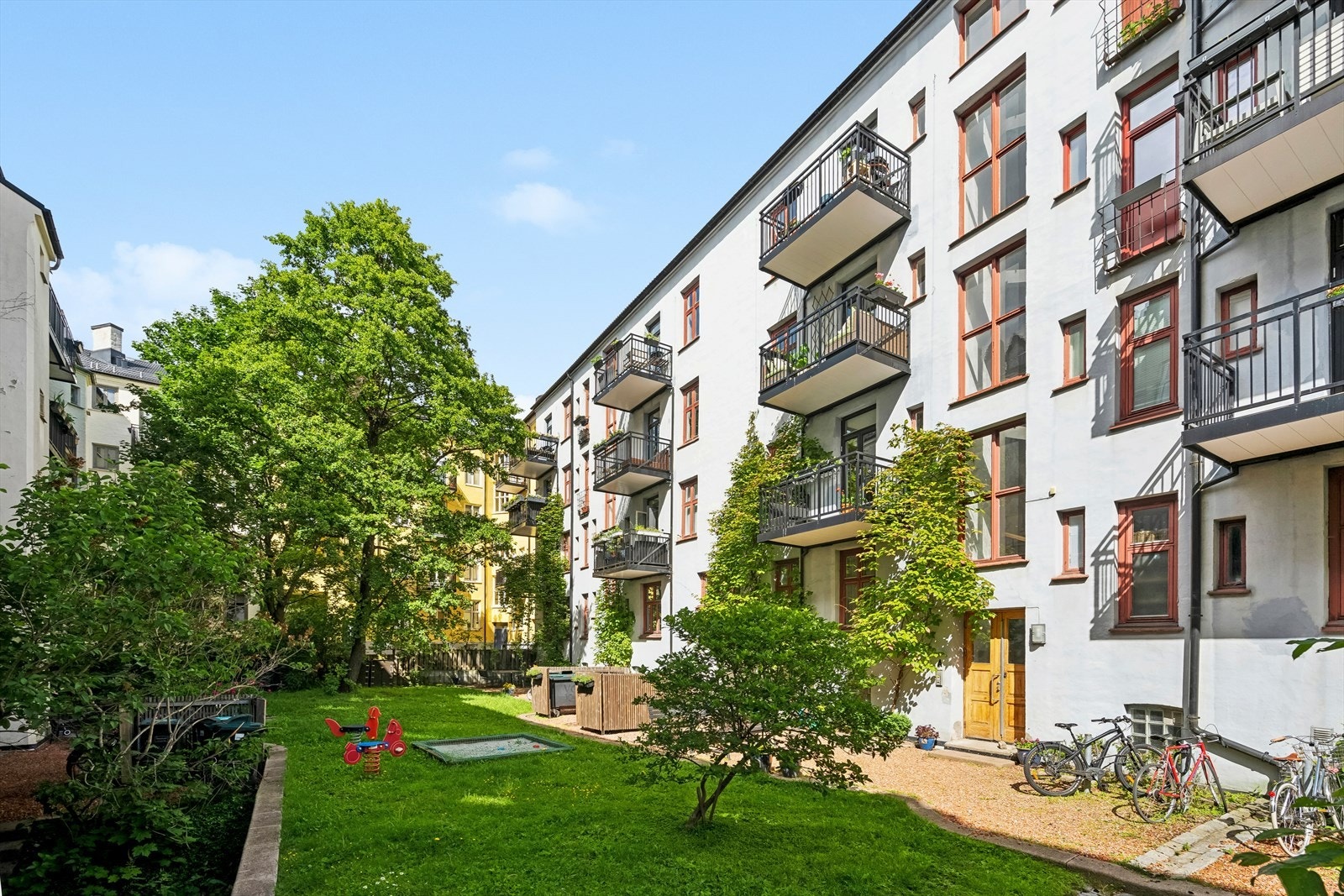 Bakgården er pent opparbeidet med gressplen, trær og diverse beplantninger, samt sittegrupper, lekeapparater og gruslagte internveier. Galleribilde