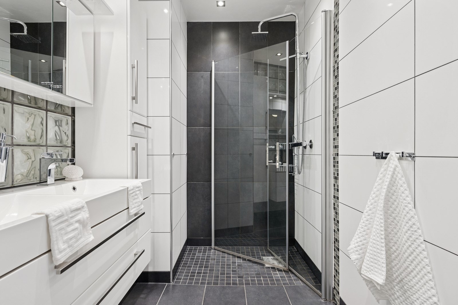 Baderomsinnredningen er bestående av dobbel servant med skuffeseksjon, speilskap, vegghengt klosett og dusjhjørne med svingbare glassdører. Galleribilde