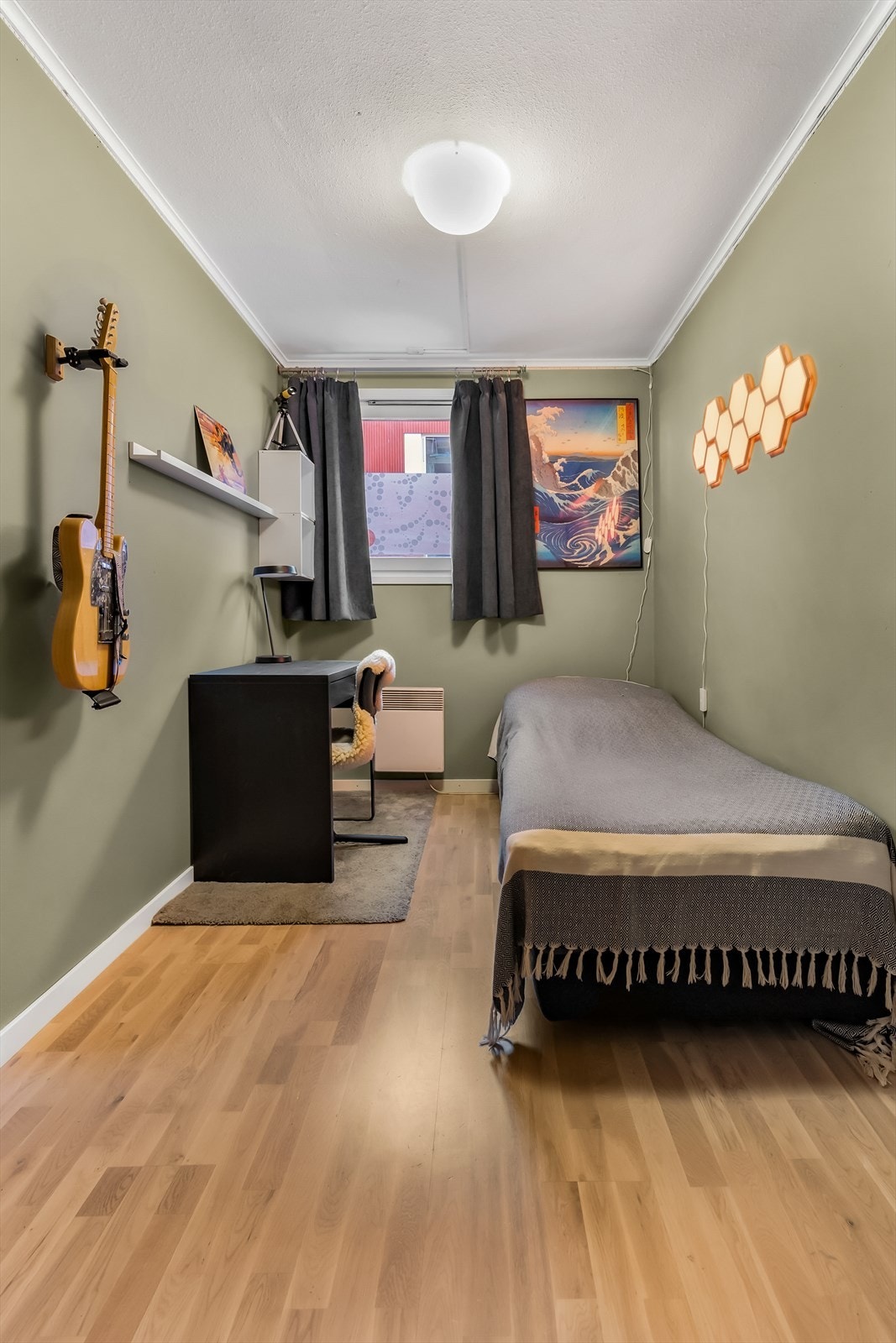 Romslig soverom med plass til nattbord, kontorpult, seng og garderobeskap. Rommet er malt i en lun behagelig grønnfarge. Galleribilde