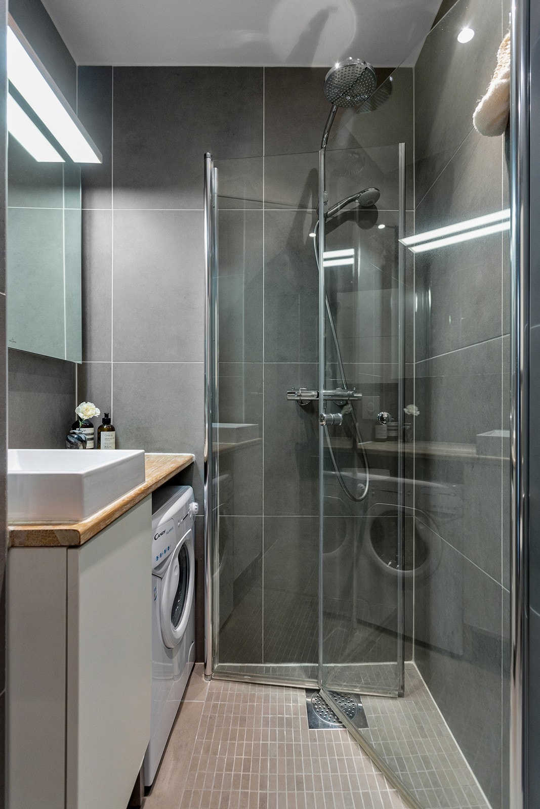 Moderne bad med varmekabler, dusjnisje, veggmontert servantinnredning og opplegg for vaskemaskin. Galleribilde