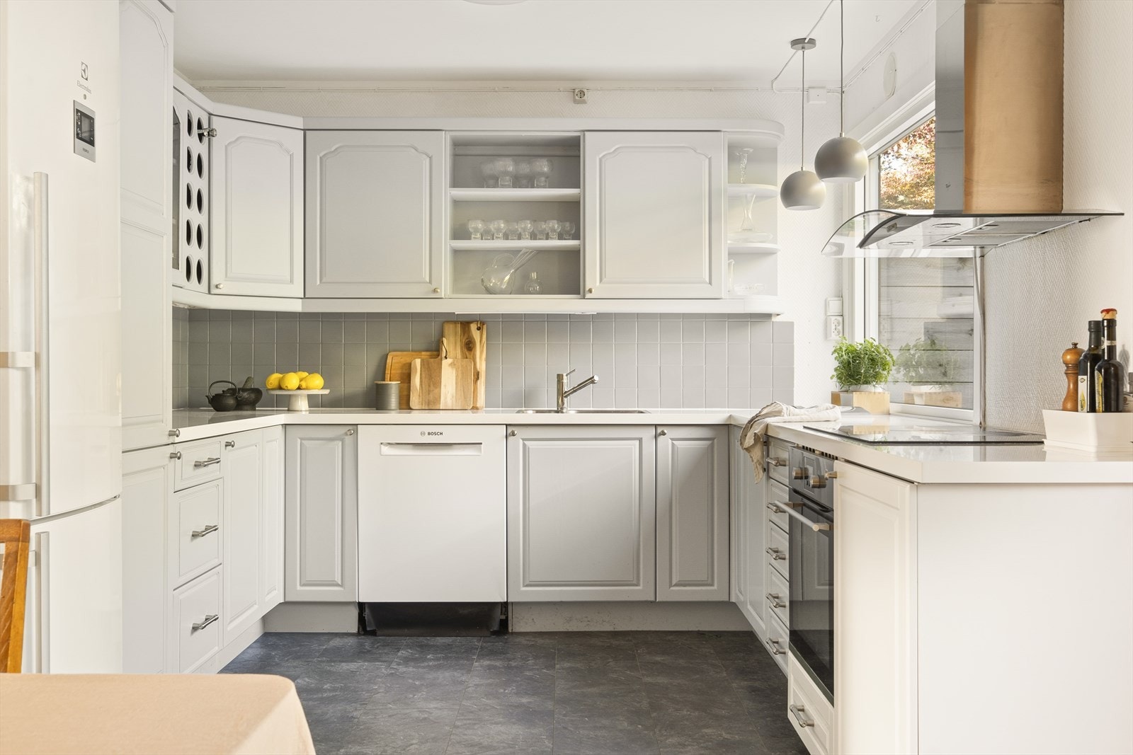 Boligen har et stilrent og innbydende kjøkken. Her er det godt med skap- og benkeplass. Kjøkkeninnredning med laminerte benkeplater, flislagt backsplash, profilerte fronter og ventilator med utkast til friluft. Galleribilde