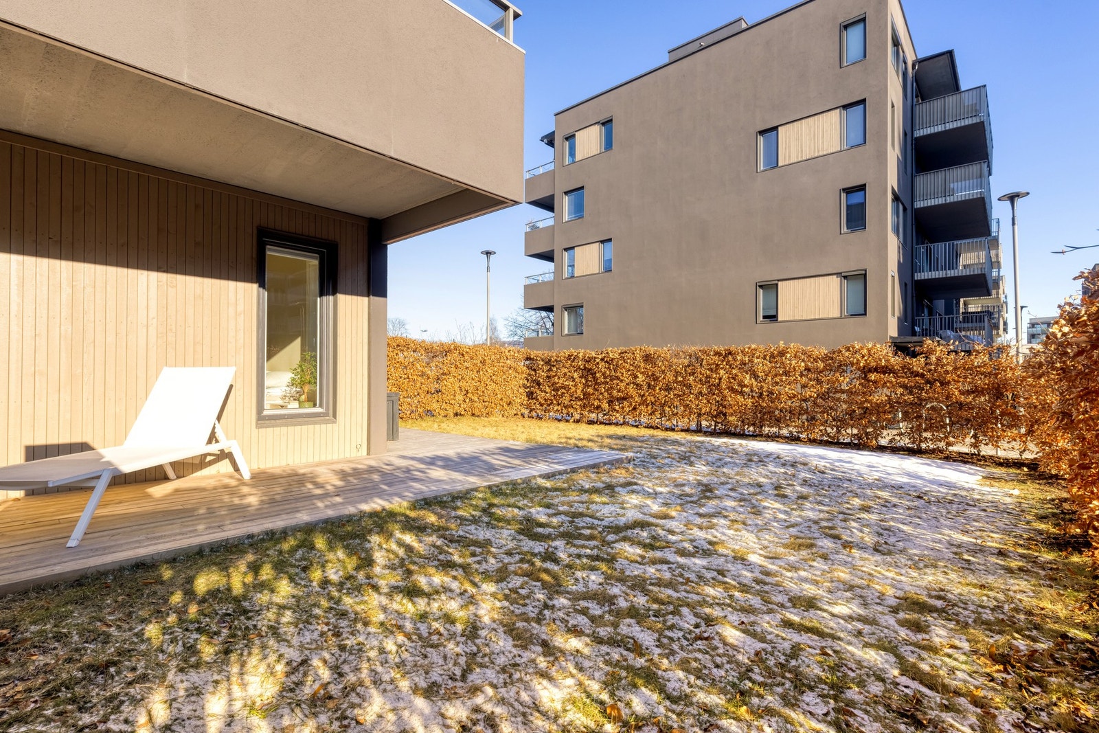 Uteplassen og leiligheten omkranses av tykk hekk som skjermer for innsyn. Galleribilde
