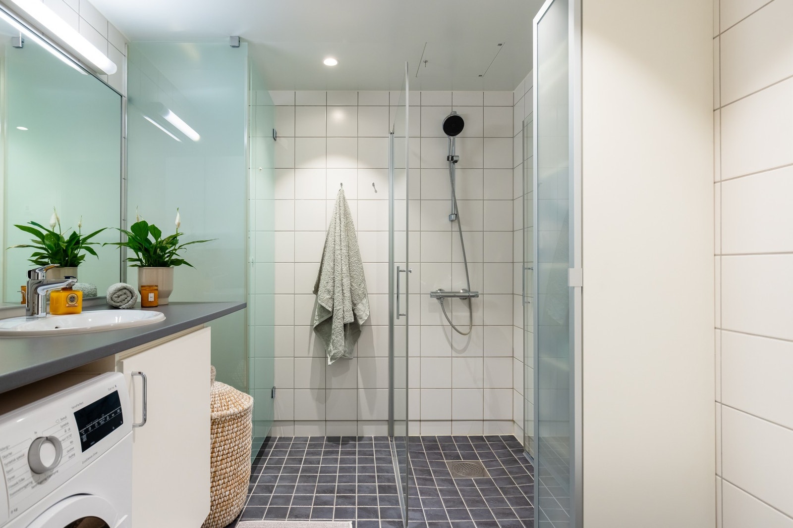 Badet har dusjhjørne med glassvegger, vegghengt toalett og et praktisk tørkeskap. Galleribilde