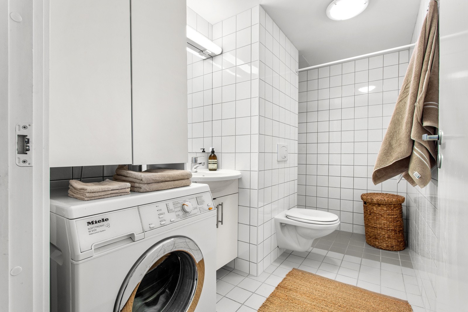 God størrelse på badet (prefabrikert bad fra 2007/2008) innredet med hvit baderomsinnredning og høyskap med slette fronter, ovenpåliggende servant, speil og veggbelysning. Galleribilde