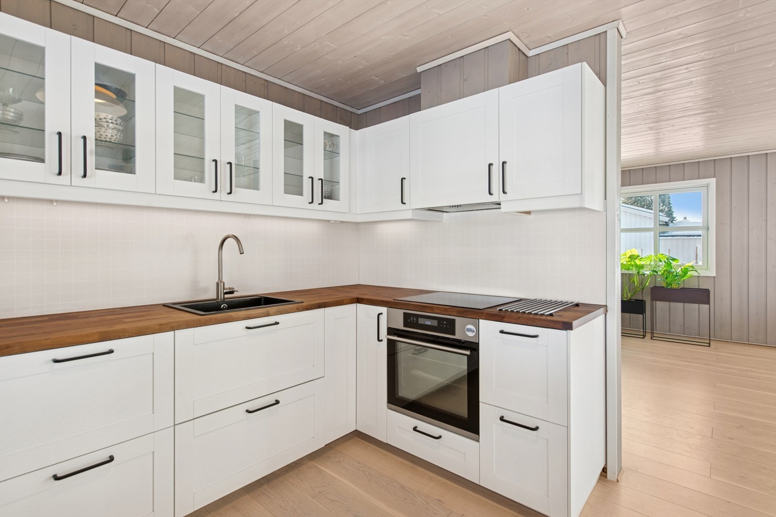 Innredning fra 2016 med laminerte skrog, profilerte fronter, innfelt glass i overskapene og heltre benkeplate med oppvaskkum i kompositt. Galleribilde