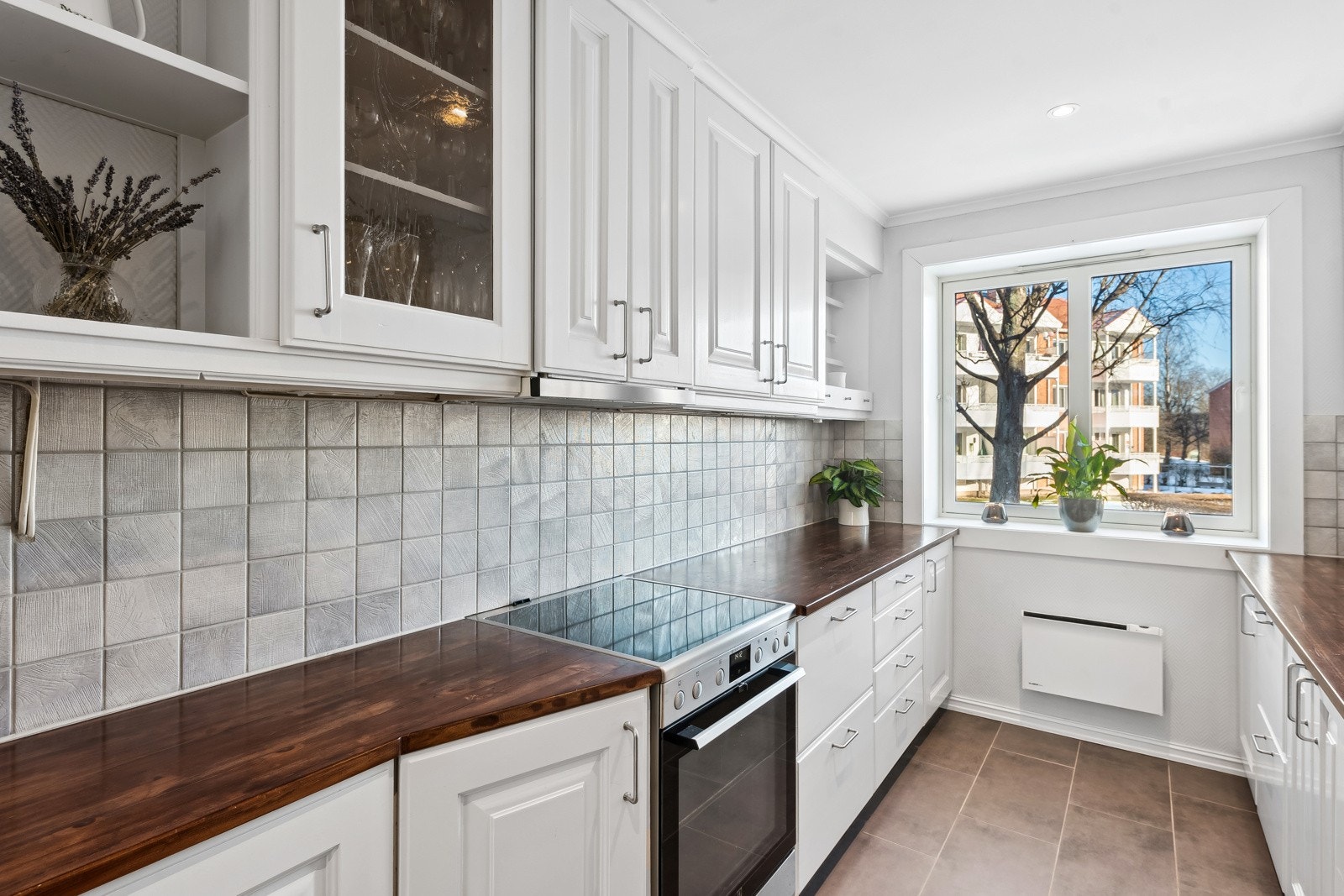 Fliser over kjøkkenbenk, delvis glass i overskap. Nisjehyller. Fint med eget kjøkkenrom. Galleribilde