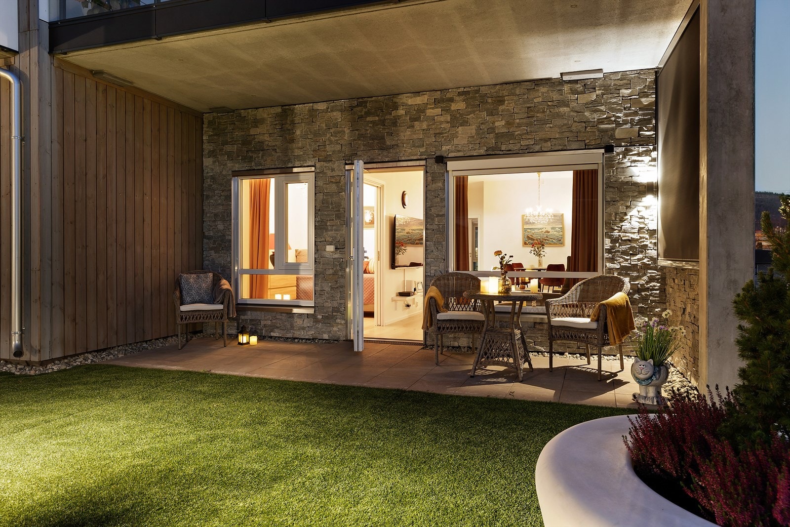 Fra terrassen er det utgang til flott uteplass med terrasseplatting. Dette er en lun og fin uteplass med fasadebelysning av bl.a.skifersteinen på kledningen av bygget Galleribilde