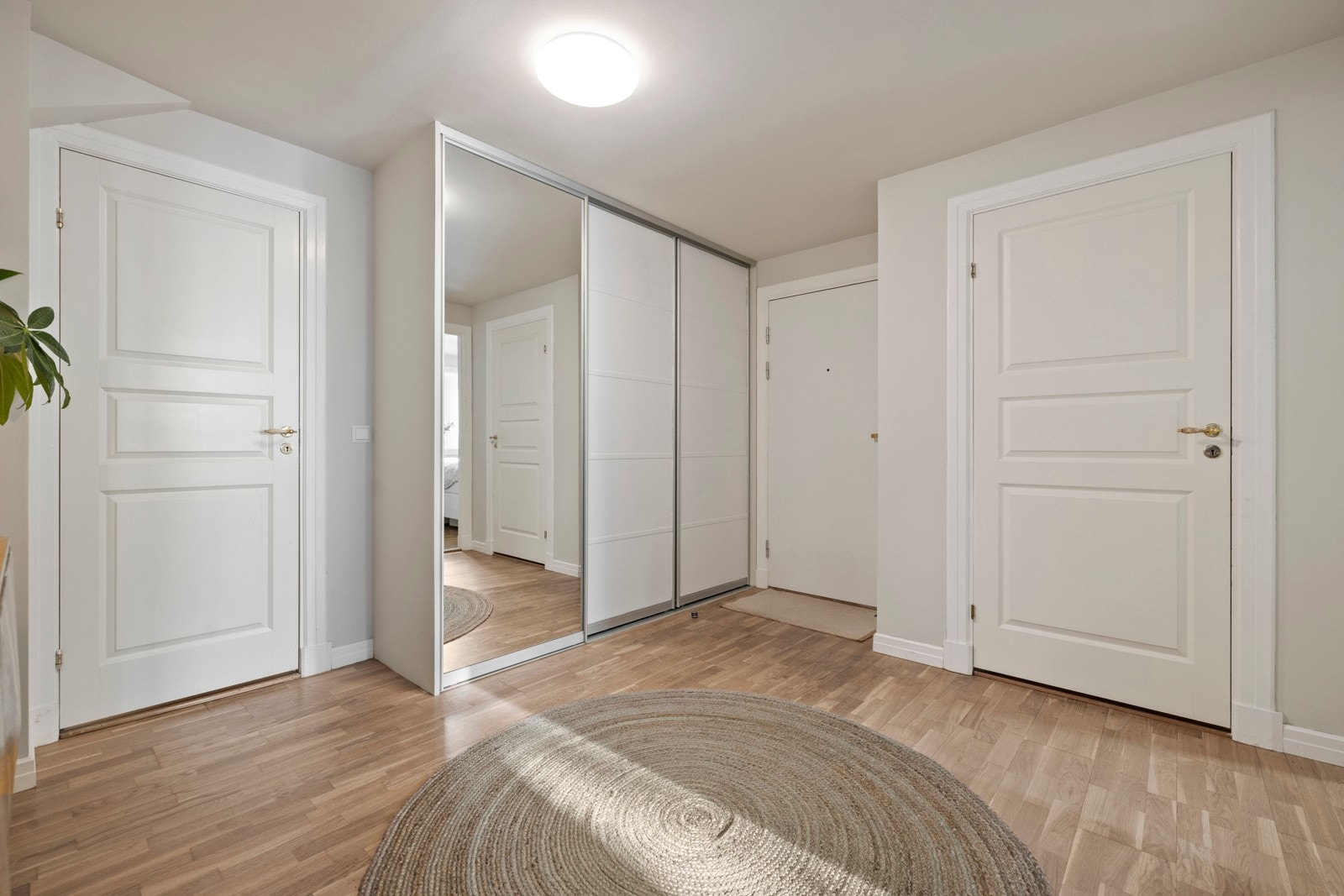 Romslig inngangsparti som gir et godt førsteinntrykk av boligen. Her er det plass til å henge fra seg klær og annet på knagger, samt oppbevare ytterligere i en romslig, integrert skyvedørsgarderobe med speil. Galleribilde