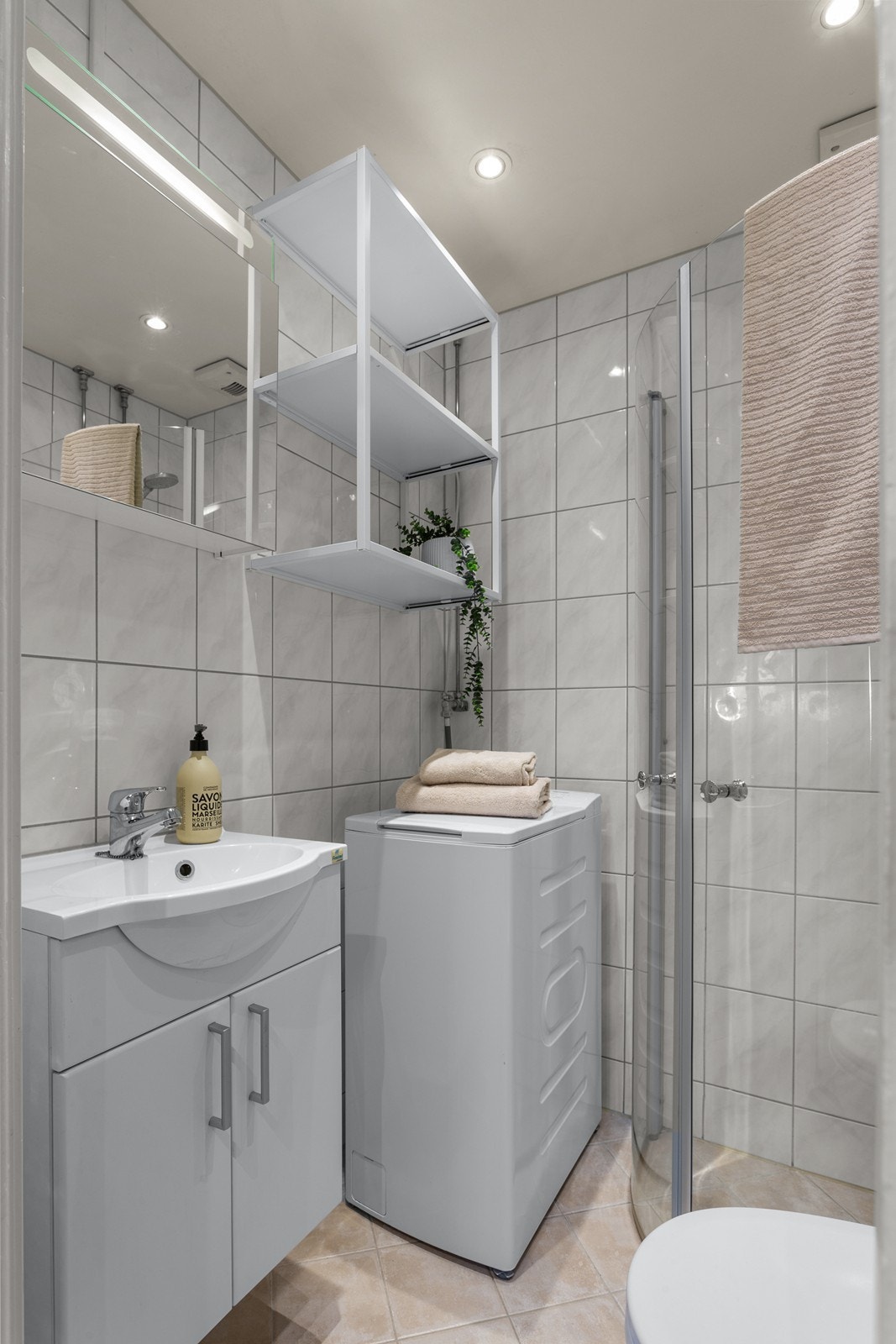 Badet har en innredning bestående av vegghengt klosett, servantinnredning, servant med ettgreps blandebatteri, dusjdører, dusjarmatur, opplegg og plass til vaskemaskin. Galleribilde