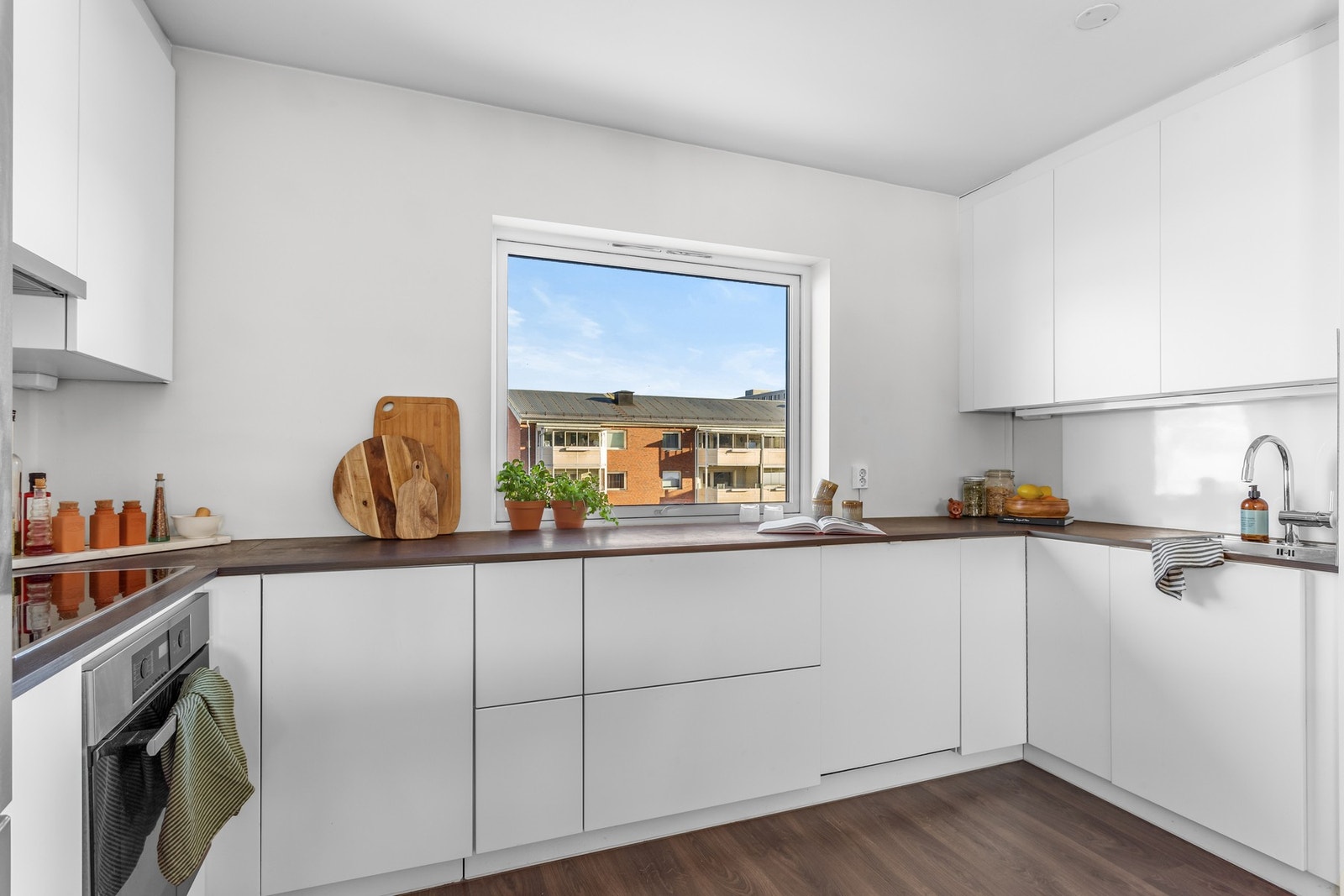 Her er det laminat benkeplate med integrert kum i rustfritt stål, lys under overskapene og praktiske plexiglassplater over benkeplaten ved komfyren og oppvaskkummen. Galleribilde