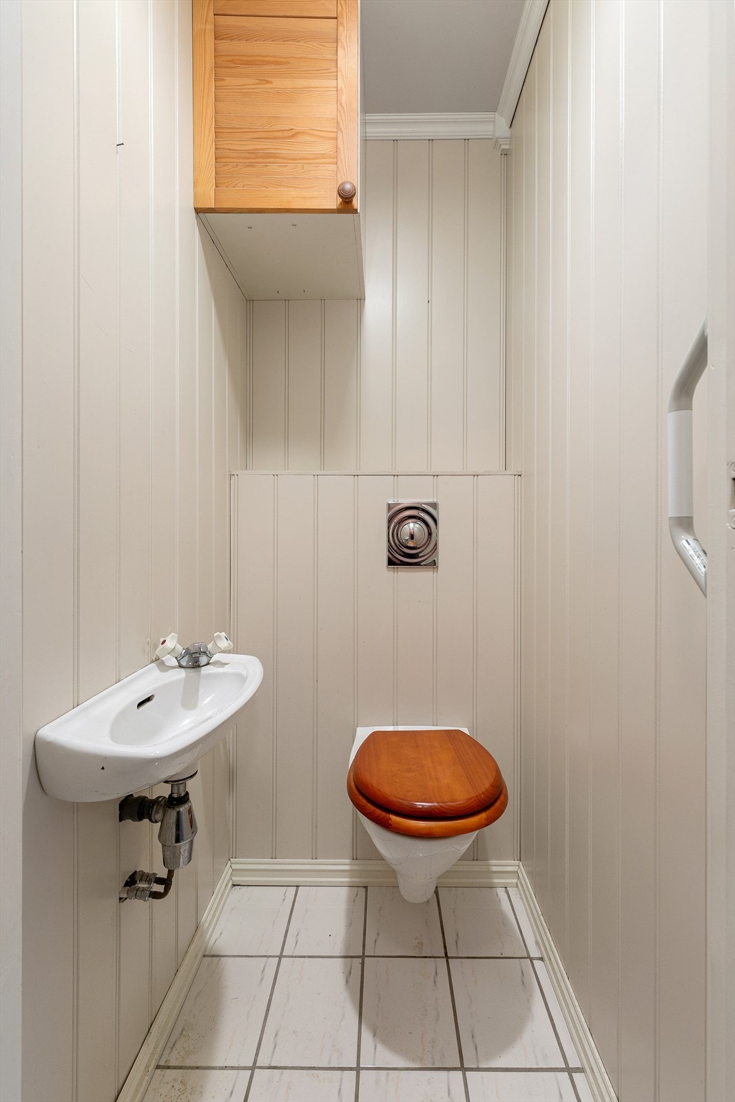 Vegg i vegg finn me eit enkelt wc-rom utstyrt med vegghengt toalett og servant. Galleribilde