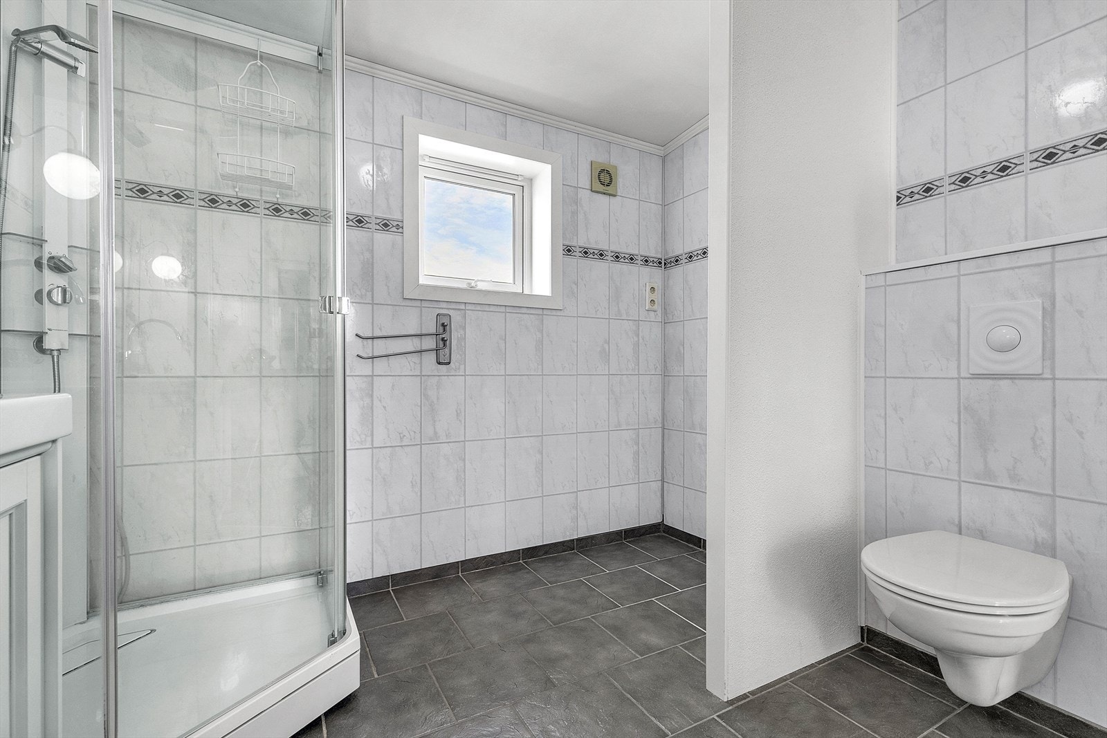 Videre er badet utstyrt med veggehengt toalett og praktisk løsning for vaskemaskin. Galleribilde