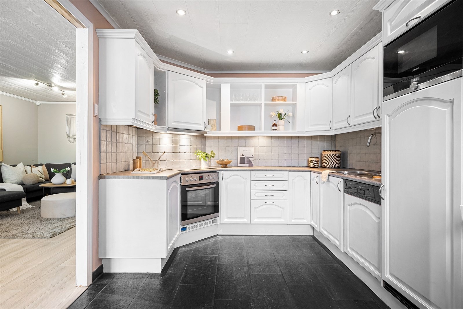 Kjøkkenet måler 12,5 m² og har laminert benkeplate og hvitmalte trefronter. Galleribilde