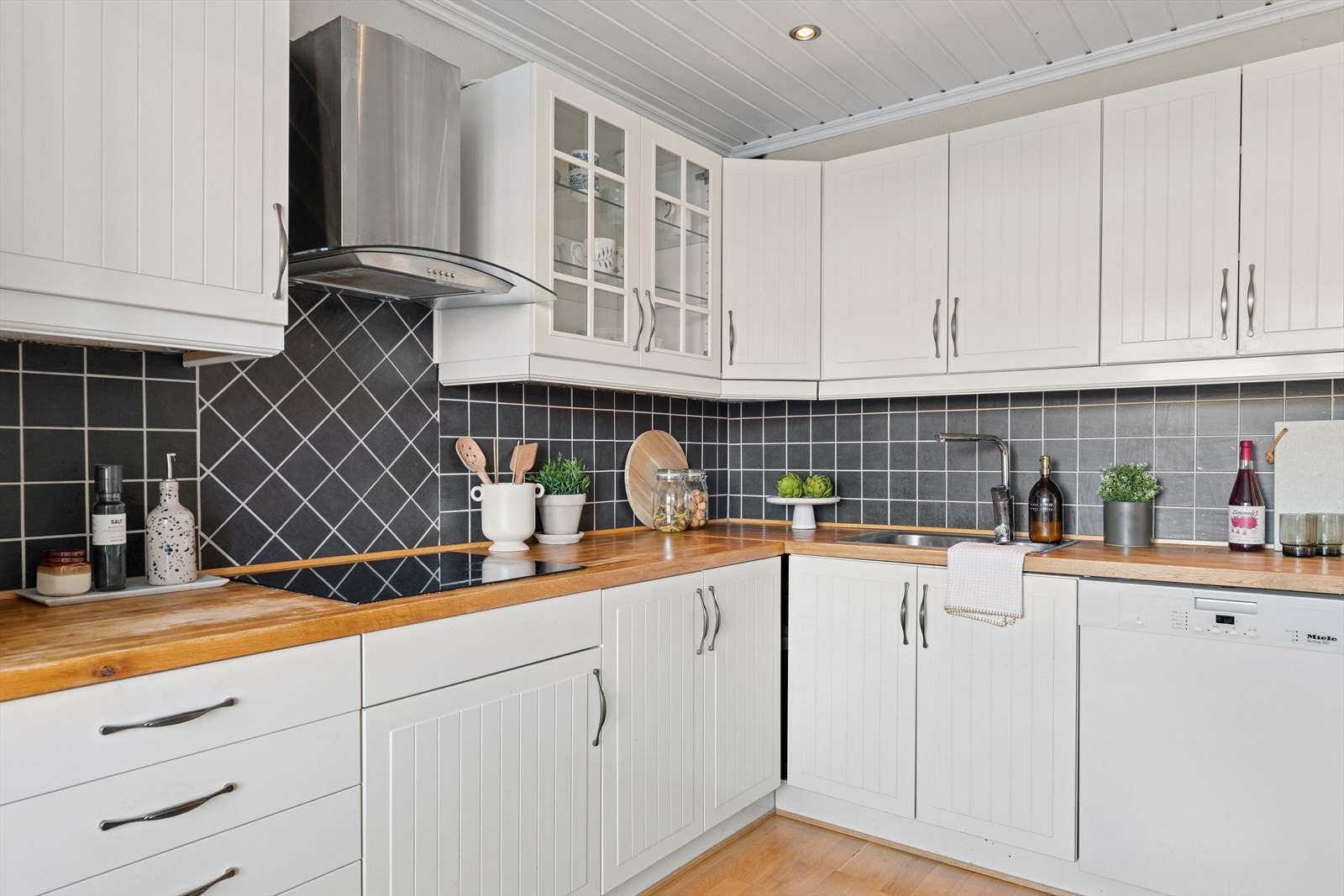 Innredningen har profilerte fronter og en benkeplate i heltre eik, utstyrt med nedfelt stålkum og ettgreps kjøkkenkran. Galleribilde