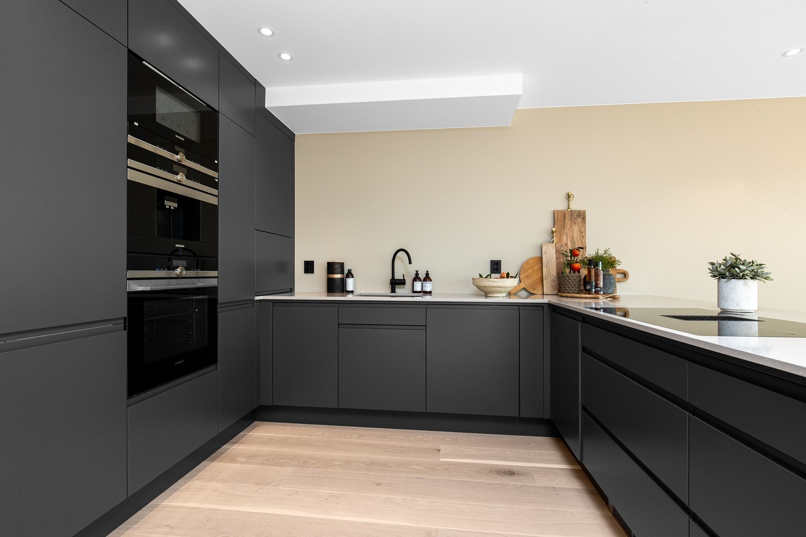 Stilfullt kjøkken med integrerte hvitevarer og benkeplate i kompositt stein. Galleribilde