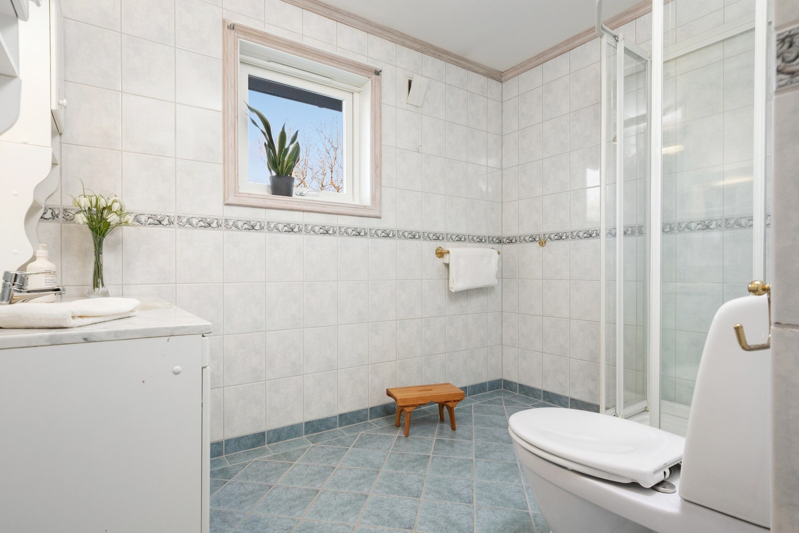 Badet ble pusset opp på 2000-tallet og har lyse fliser på veggene, mørkere fliser på gulvet, gulvvarme, toalett og dusjkabinett Galleribilde