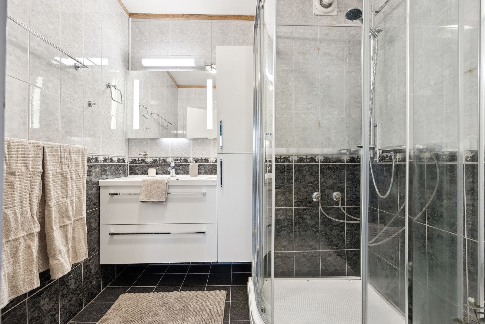 Bad med flislagt gulv og vegger med dusjkabinett. Galleribilde