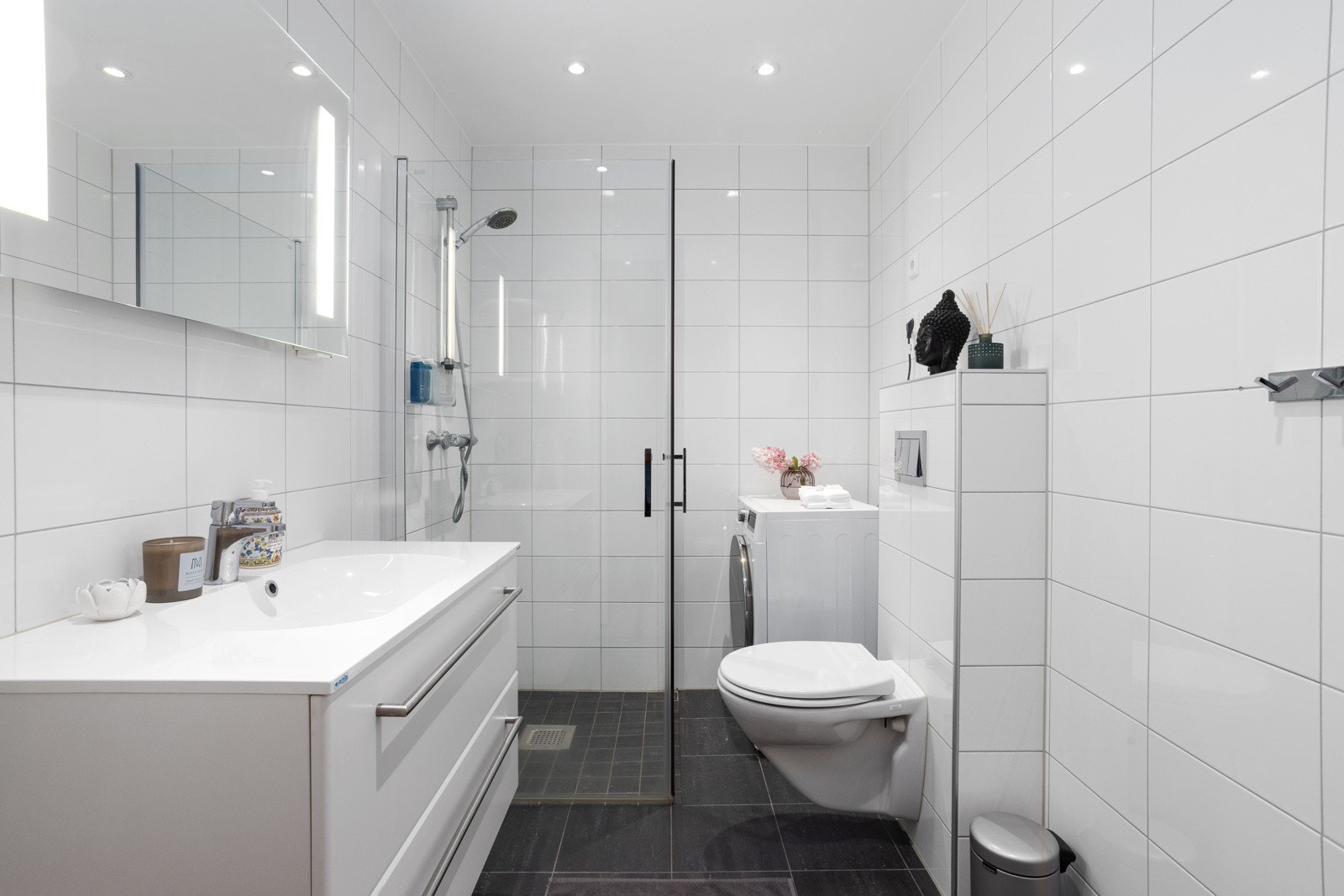 Delikat flislagt bad med gulvvarme. Baderomsinnredningen består av vegghengt toalett, dusjhjørne med innfellbare glassdører og opplegg til vaskemaskin Galleribilde