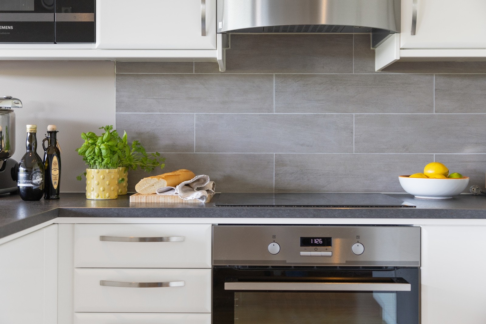 Det er pent flislagt mellom under- og overskap. Vegghengt ventilator med montert komfyrvakt Galleribilde