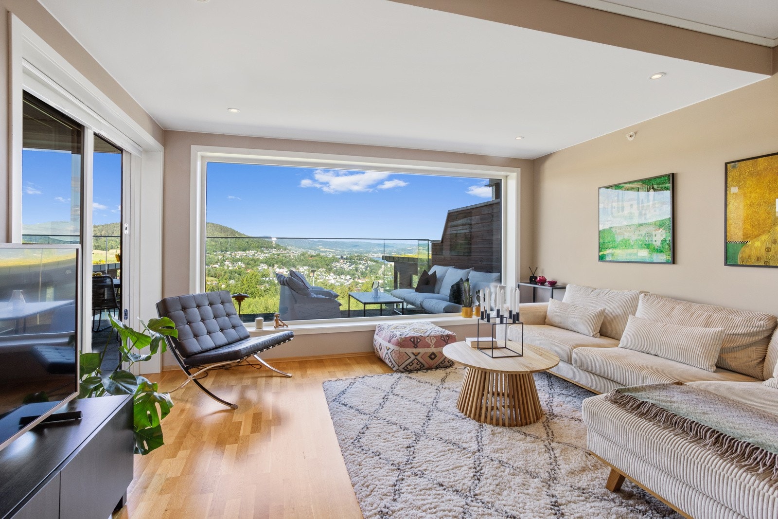 Koselig stuedel med et stort vindu som strekker seg fra vegg-til-vegg og ned til gulv. Det er montert utvendig solskjerming på vinduet, styrt via fjernkontroll Galleribilde