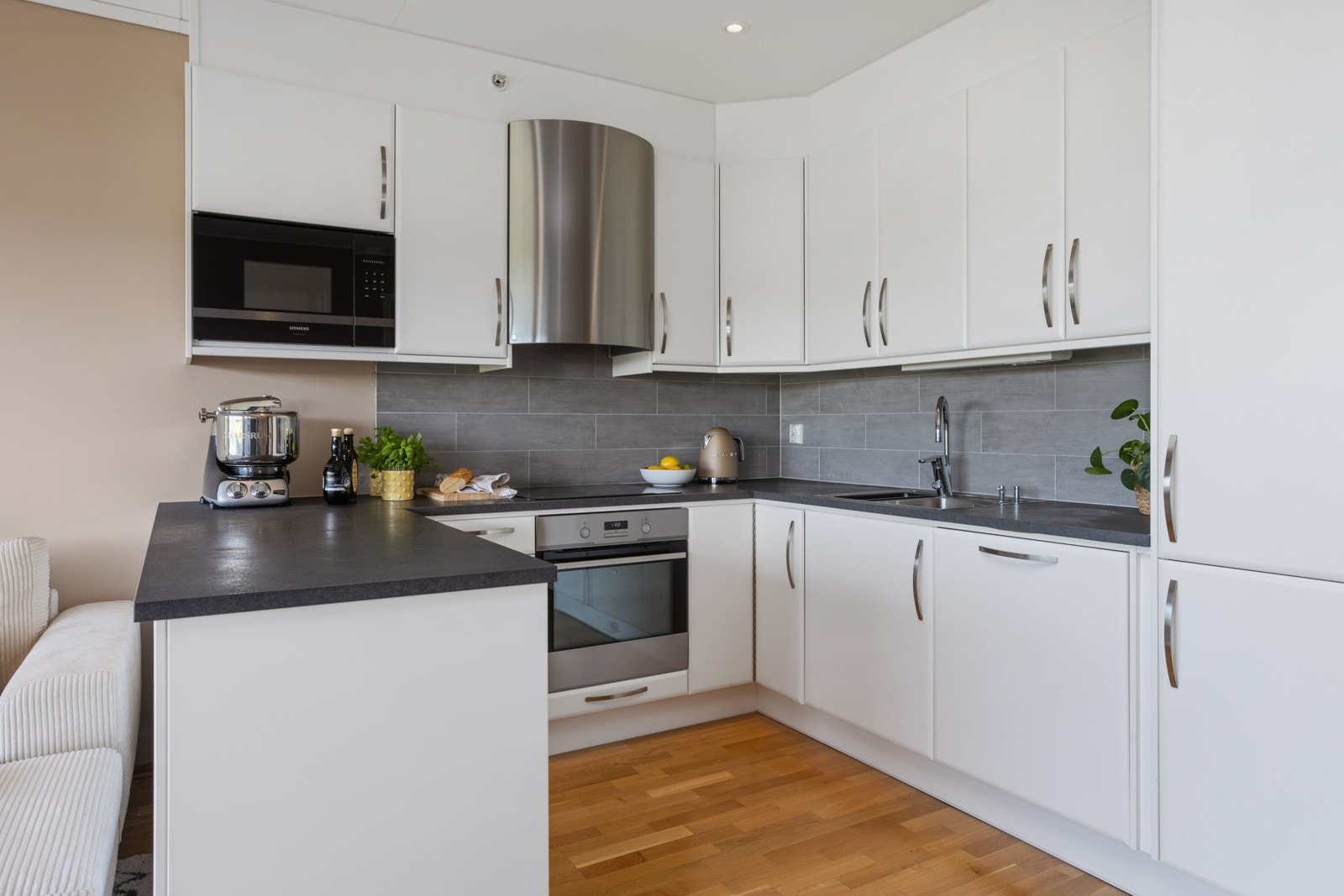 Smakfull kjøkkeninnredning levert av Drømmekjøkken, i klassisk hvit utførelse med slette fronter. Kjøkkenet har god skap- og benkeplass Galleribilde