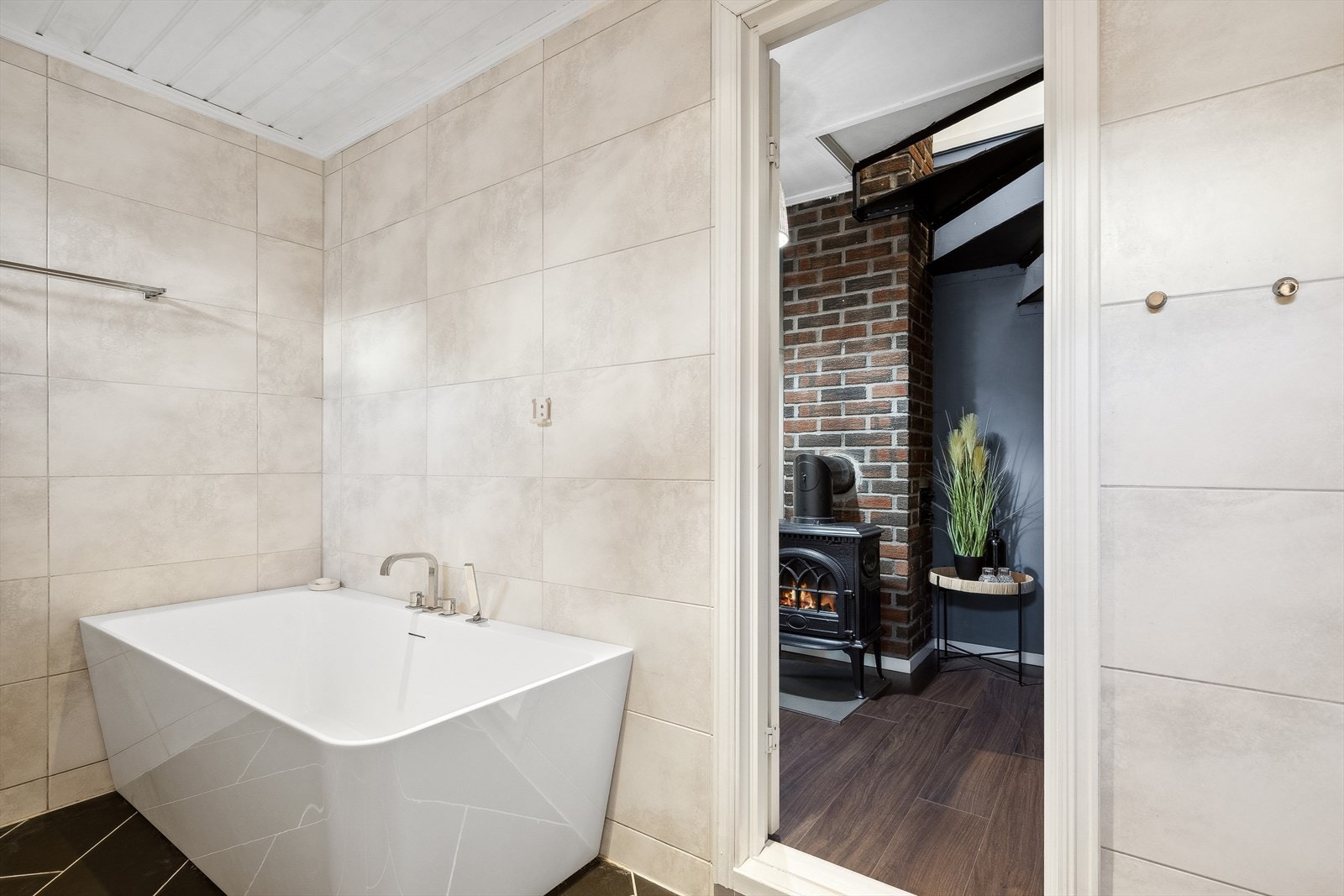 Badet er innredet med en baderomsinnredning med heldekkende servant, speil med overliggende lys, veggmontert toalett, dusj med innfellbare dusjdører og boblebadekar. Galleribilde