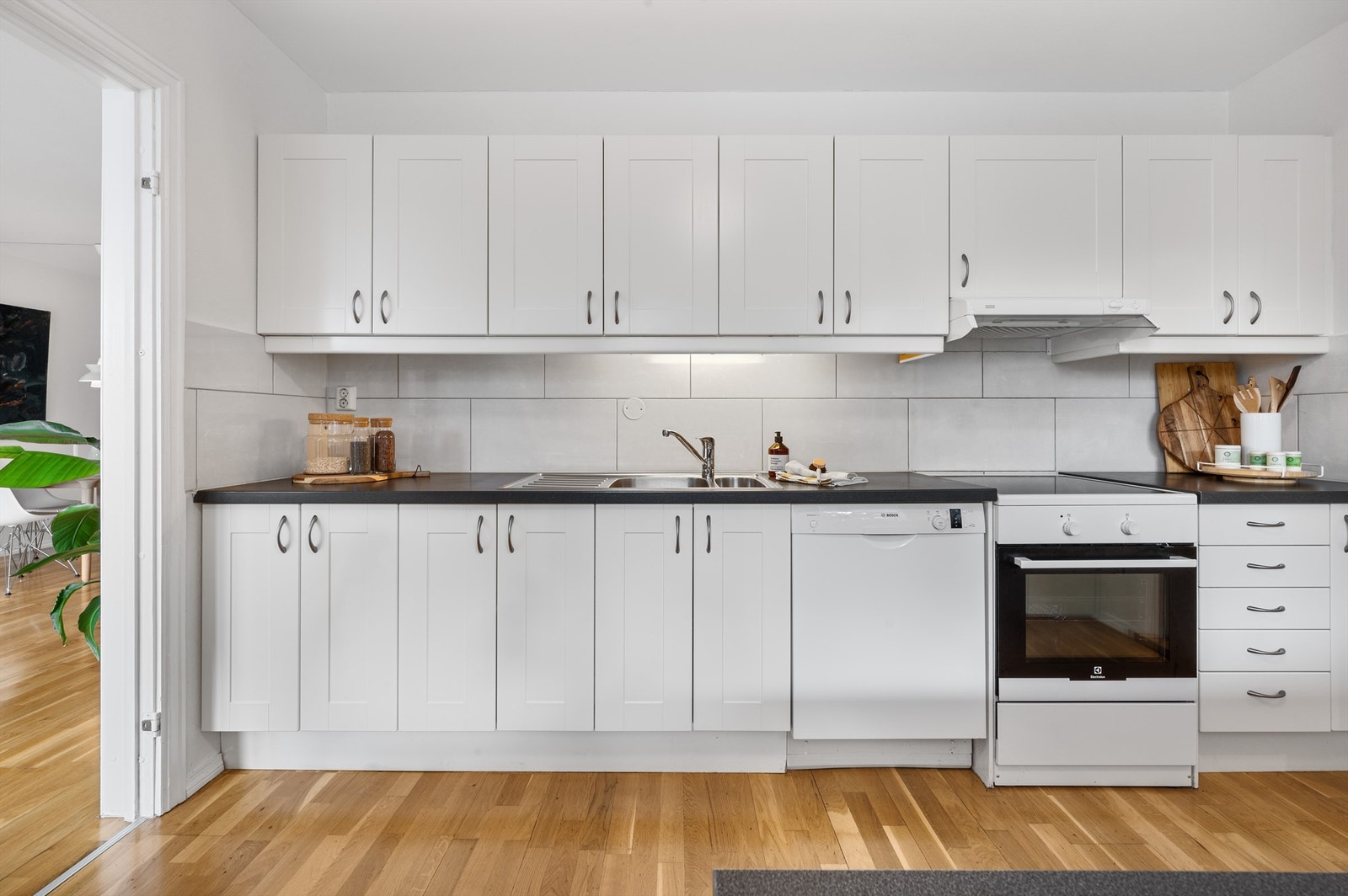 Klassisk og tidløs innredning med profilerte fronter, laminert benkeplate, nedfelt vask i stål, fliser på vegg og løse hvitevarer. Galleribilde