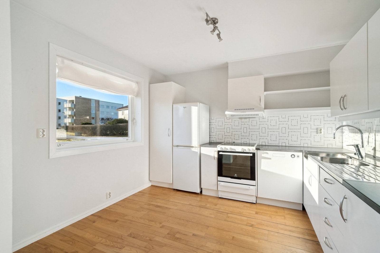 Kjøkkeninnredningen har hvite glatte fronter og en laminat benkeplate. Galleribilde