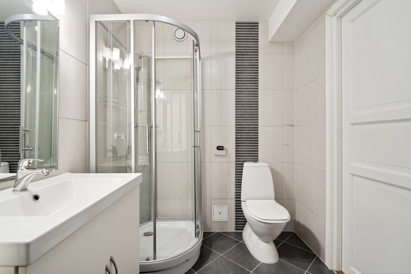 Romslig bad som er helfliset i nøytrale fargetoner, med elektriske varmekabler i gulvet. Galleribilde