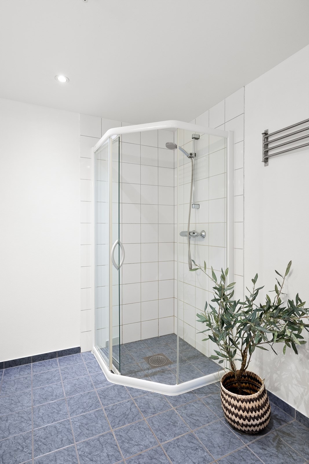 Badet er innredet med vask i seksjon, speil med belysning, vegghengt toalett og dusjhjørne. Galleribilde