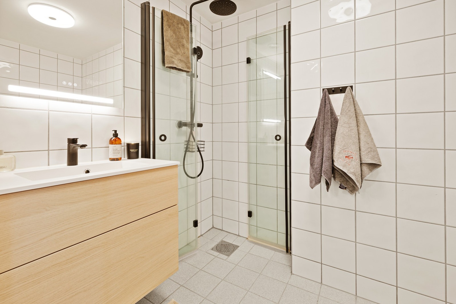 Lyst og stilrent baderom med oppgradert baderomsinnredning og dusjdører fra 2021. Galleribilde