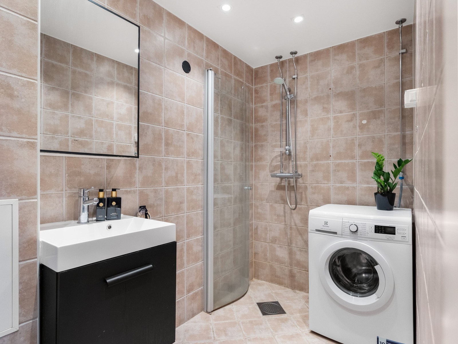 Badet har fliser på gulv og vegg og har opplegg for vaskemaskin Galleribilde