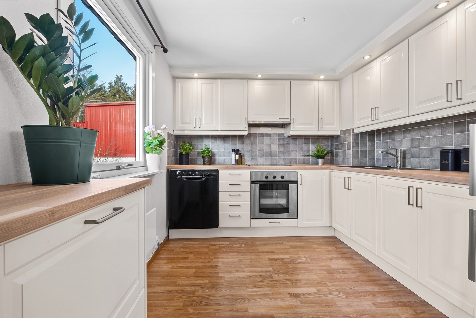 Delvis åpen kjøkkenløsning mot stue med stort vindu som bevarer utsikten for kokken Galleribilde