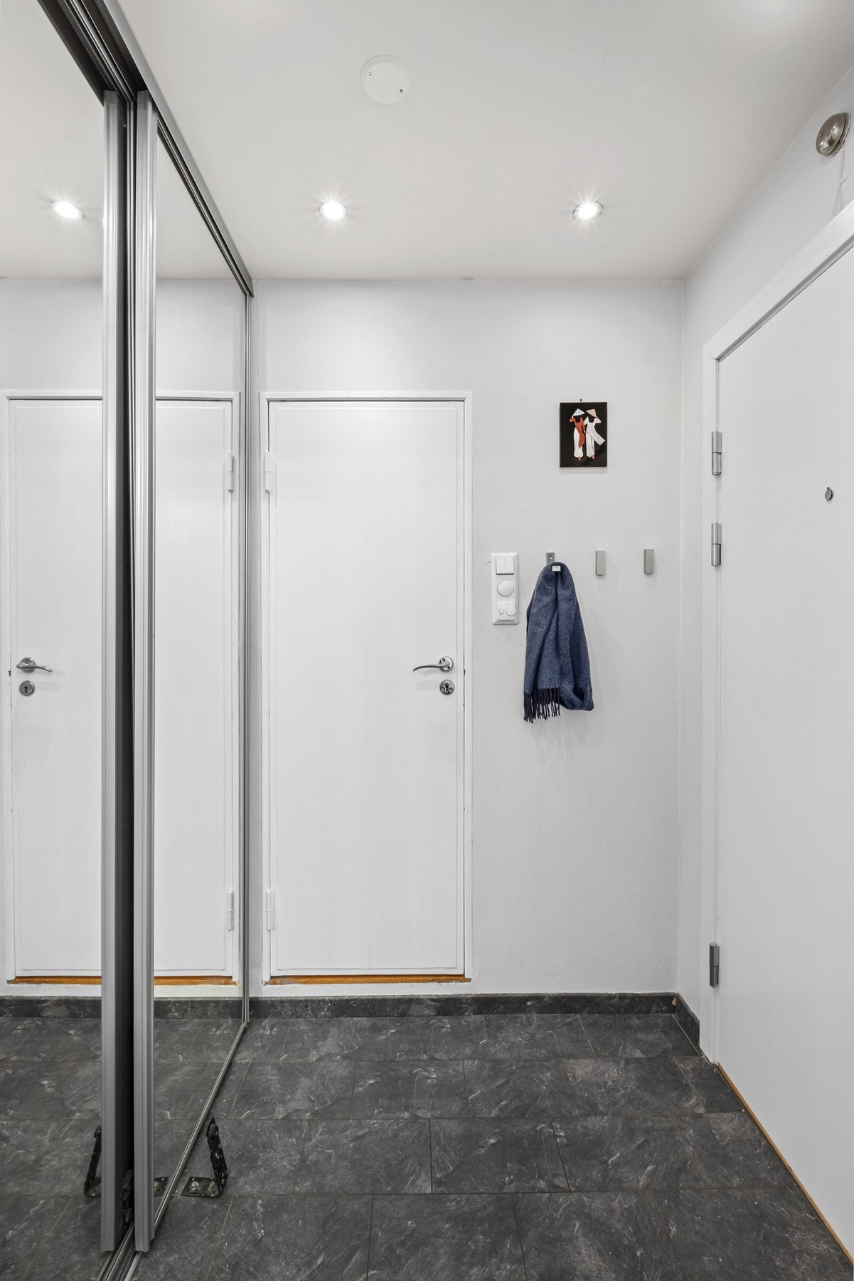 Velkommen inn! God plass til klær i garderobe, dørcalling på veggen og mørke fliser på gulv Galleribilde