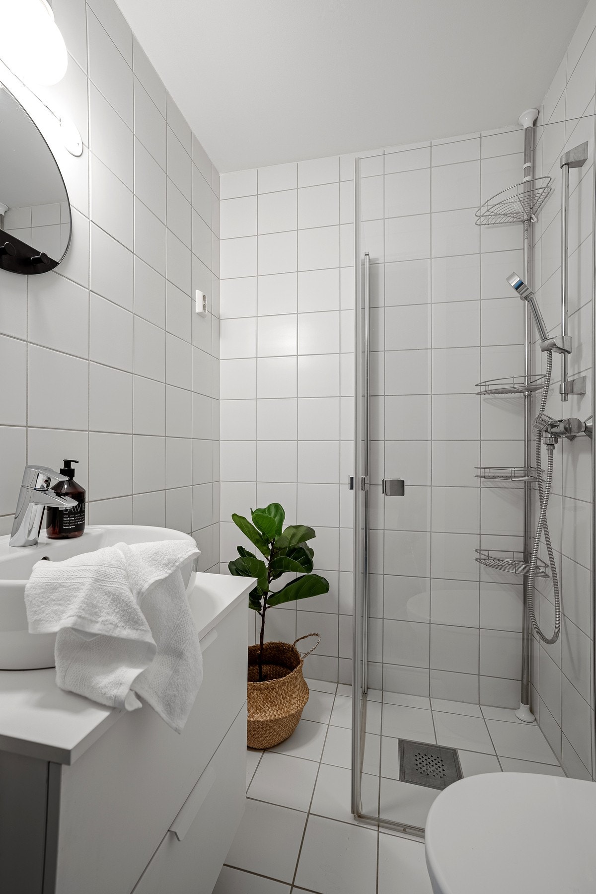 Pent flislagt bad med baderomsinnredning, dusjhjørne og opplegg til vaskemaskin Galleribilde