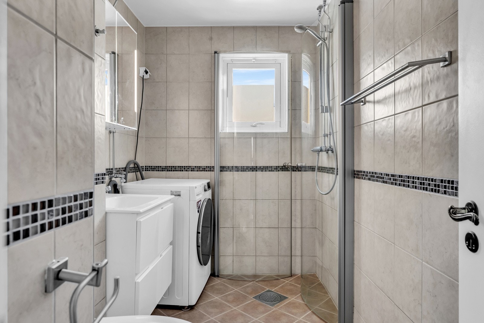 Flislagt bad med varmekabler i gulvet og opplegg for vaskemaskin. Galleribilde