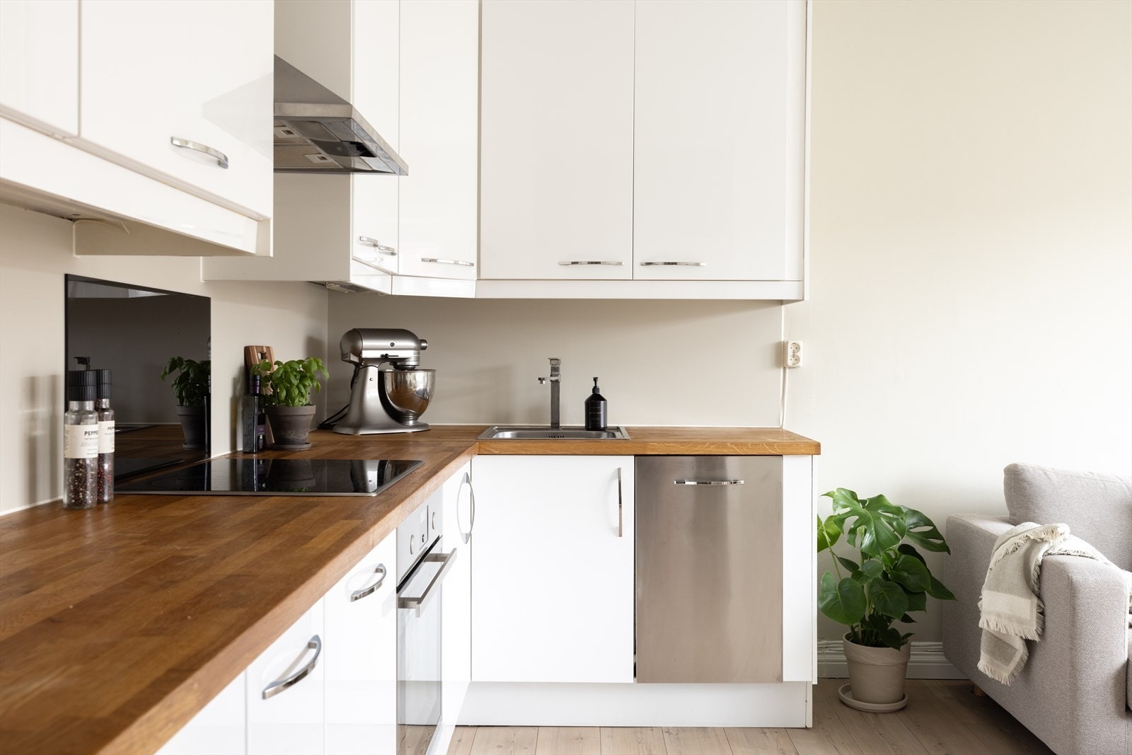 Kjøkkeninnredning med høyglans fronter og benkeplate i tre. Hvitevarer som oppvaskmaskin, platetopp og stekeovn er integrert. Galleribilde