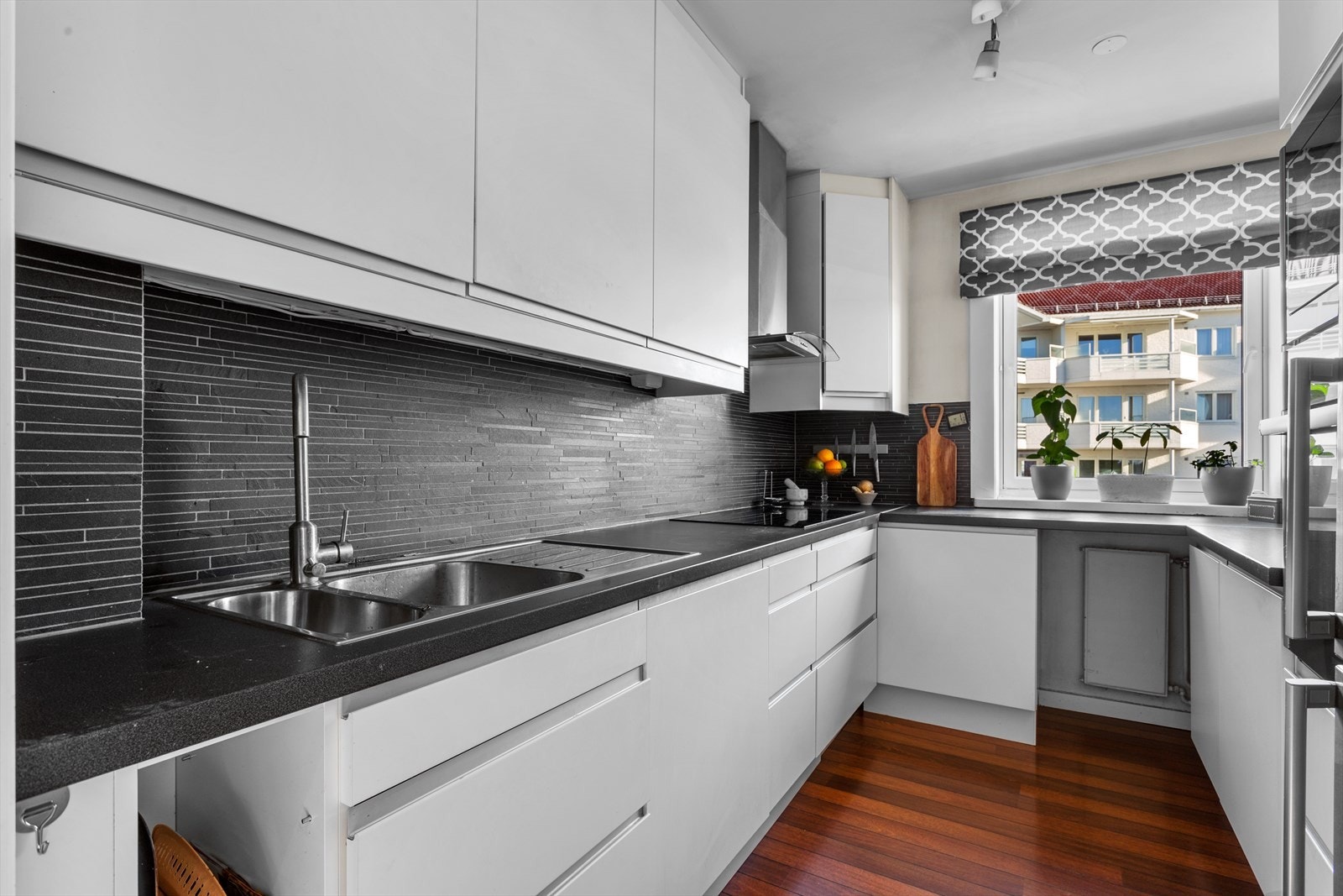 Hjemmet byr på adskilt kjøkken med en tidløs innredning bestående av hvite glatte fronter og laminat benkeplate med nedfelt kum i rustfritt stål. Galleribilde