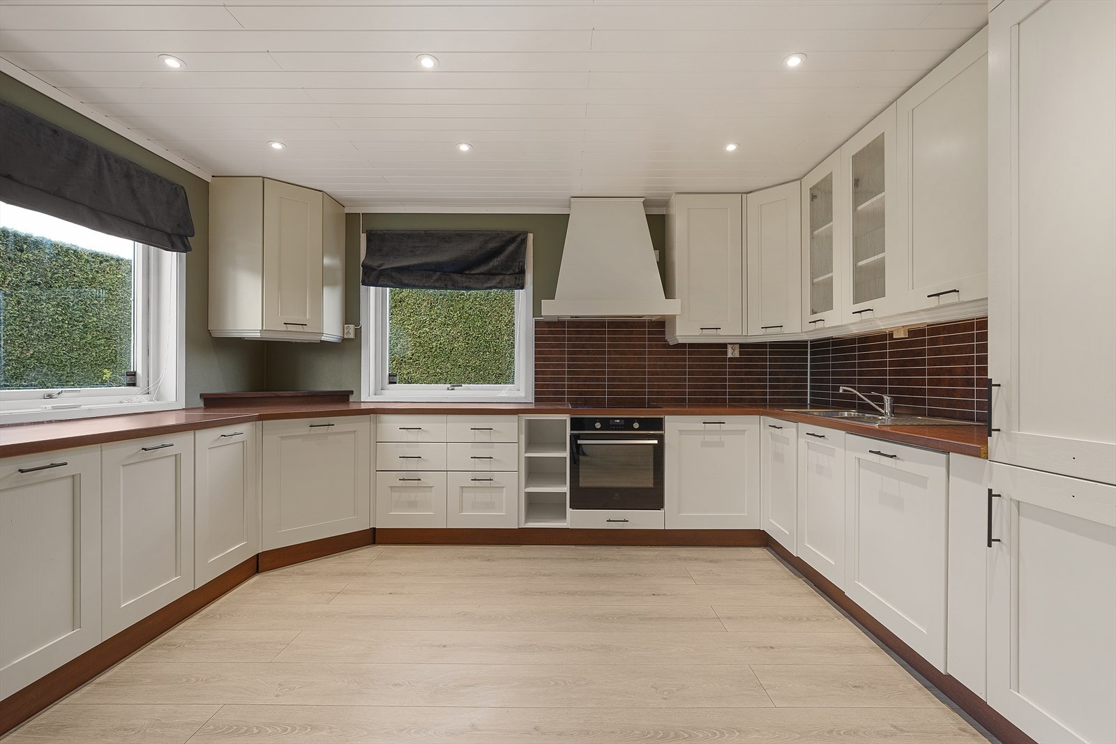 Tidløst kjøkken med hvite, profilerte fronter og laminert benkeplate. God plass til spisegruppe Galleribilde