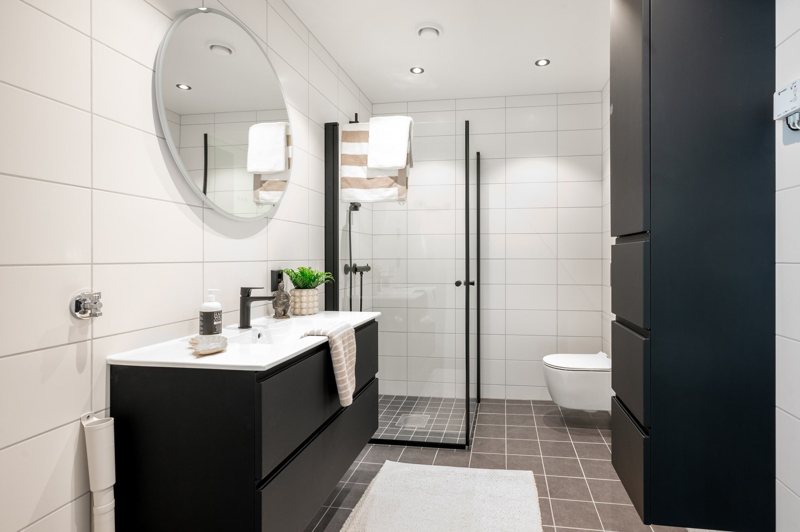 Badet er på hele 5,5 kvm., er flislagt med varme i gulv og har lekre sorte detaljer Galleribilde