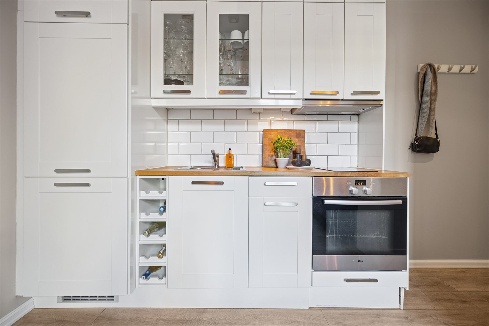 Kjøkkenet har en innredning med profilerte fronter og benkeplate av heltre. Det er flislagt mellom benkeplate og overskap, samt belysning og stikkontakt under overskap. Galleribilde