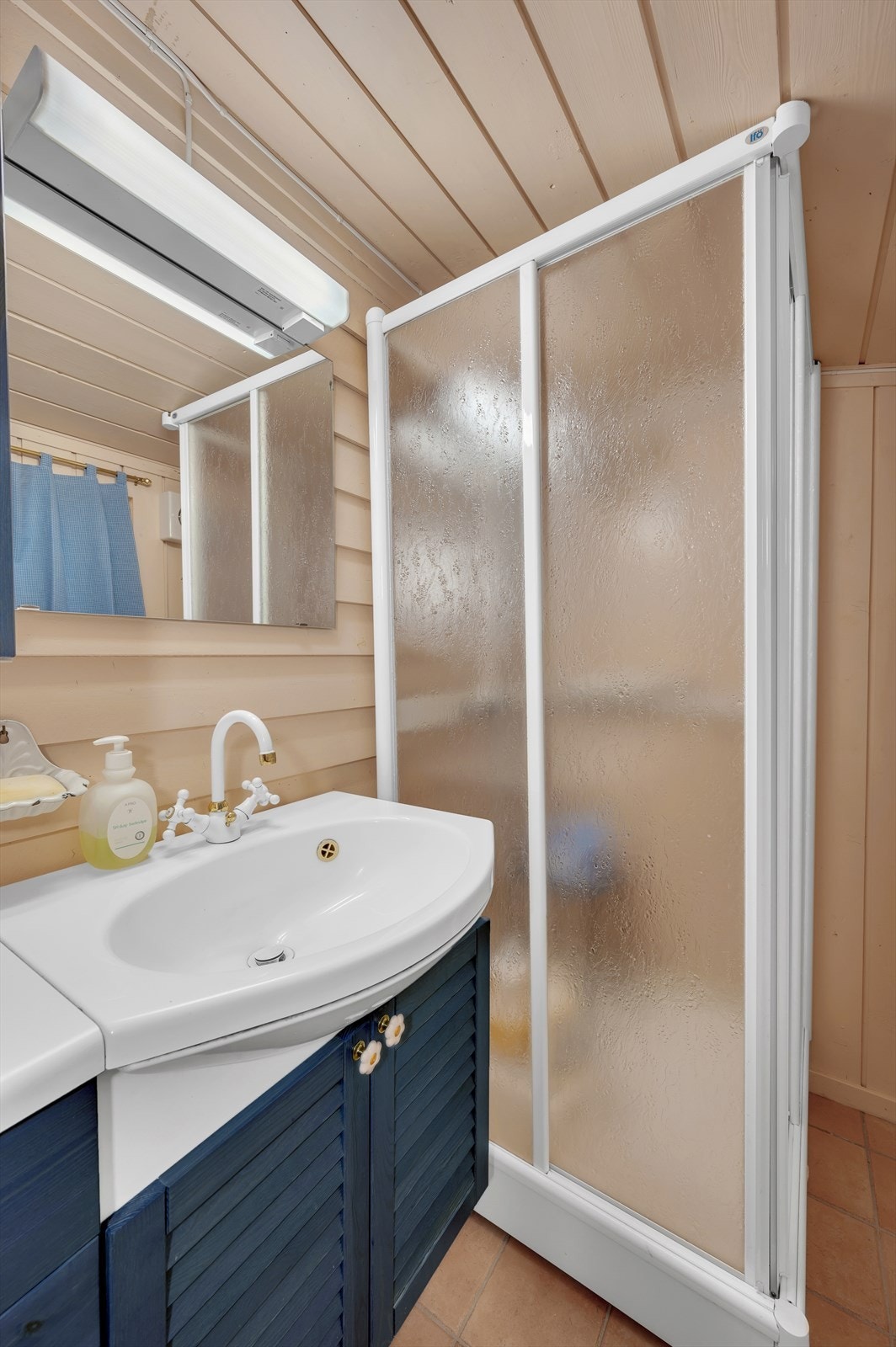 Badet inneholder et lukket dusjkabinett, skap/speil og servantinnredning med gråvannsutslipp. Galleribilde
