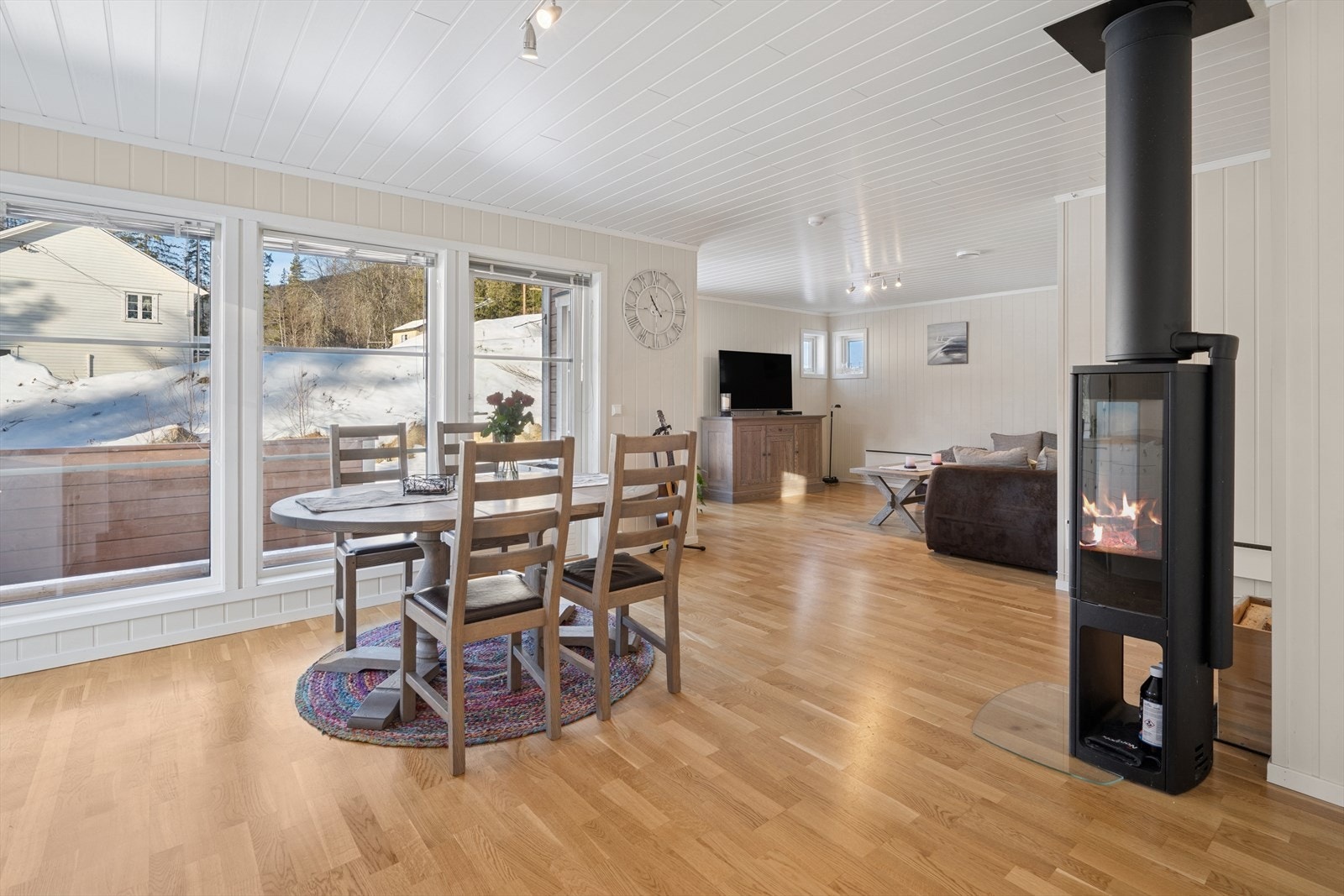 Åpen stue/kjøkken løsning med store vinduer og vedovnen som midtpunkt. Galleribilde