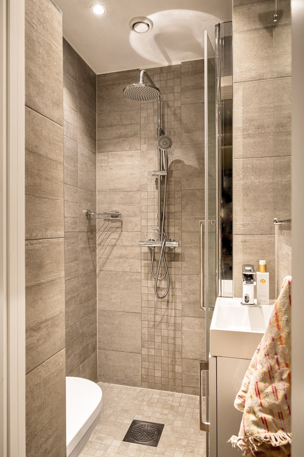 Badet har varmekabler i gulv, vegghengt toalett, 40 cm servant m/underskap og dusjnise med regnfallsdusj og glassdør. Galleribilde