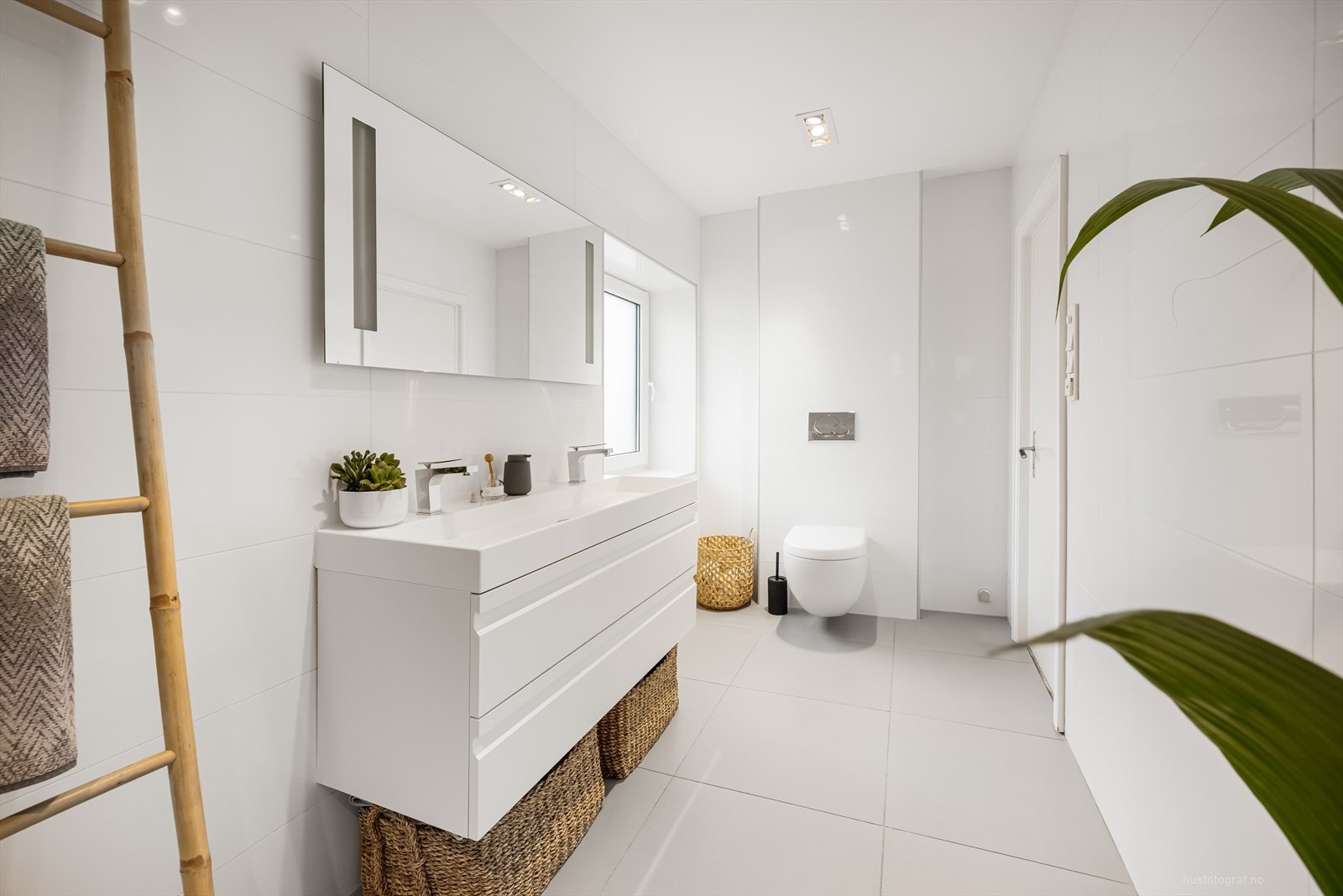 Baderomsinnredningen er lys med dobbeltservant med god oppbevaringsplass i skuffeseksjon og speil med belysning. Videre har badet vegghengt toalett og innfliset badekar. Galleribilde